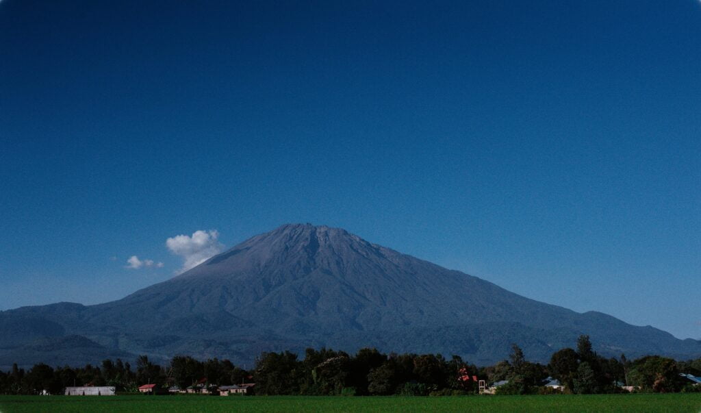 Exploring Mount Meru: Tanzania’s Hidden Gem for Trekking Enthusiasts 22 View of a Grass Field, Trees and Mount Meru under Clear, Blue Sky