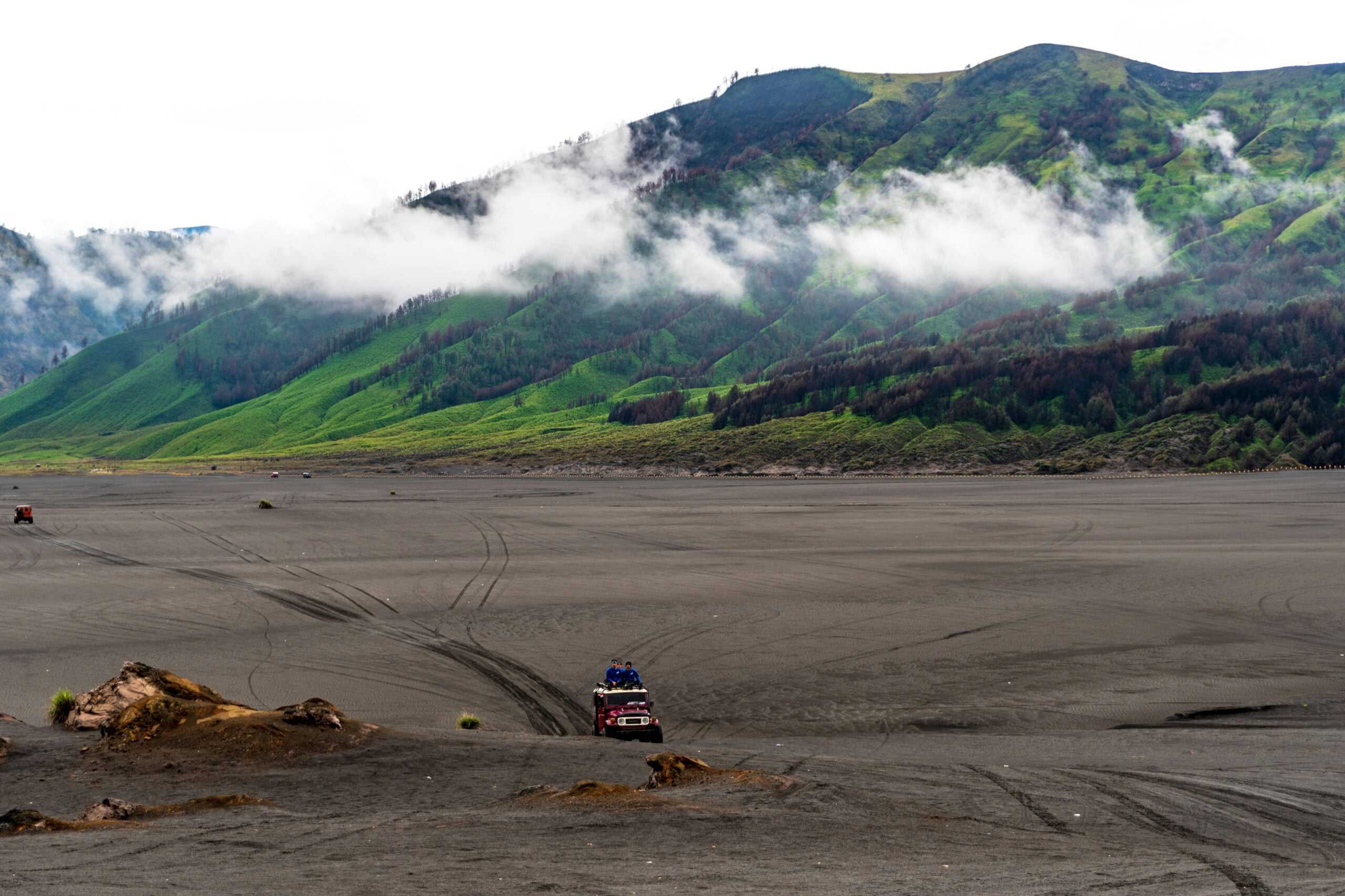 Person Riding Red Car on Vast Land Near Mountains