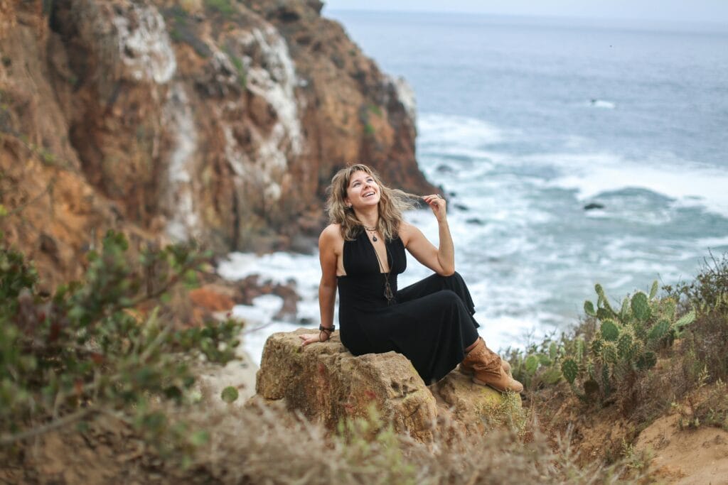 Woman Sitting on a Rock on a Seashore 