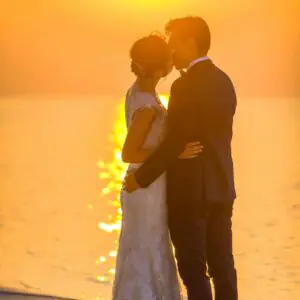 How to plan a beach wedding in Zanzibar 4 Captivating moment of a couple sharing a kiss during a beach sunset wedding, exuding romance.