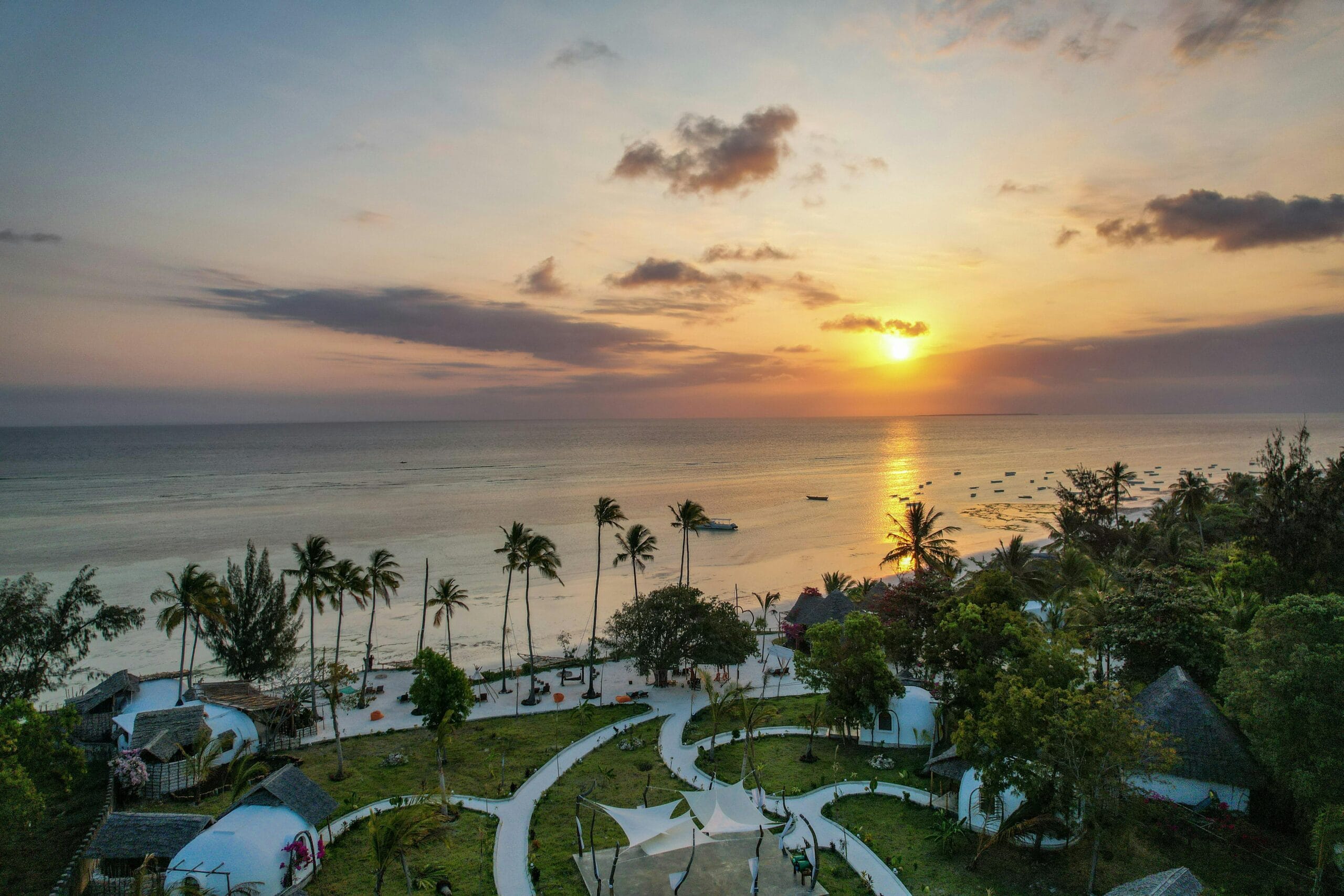 A breathtaking aerial view of Kizimkazi Beach at sunset, showcasing vibrant skies and serene waters in Tanzania.