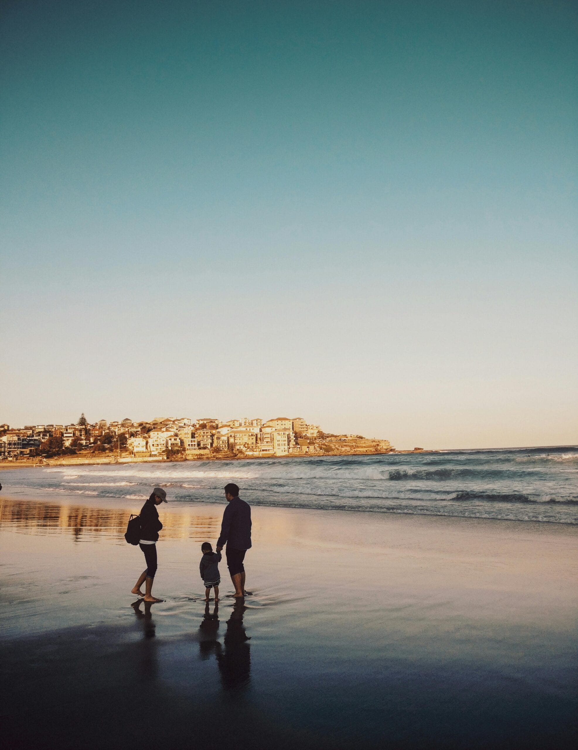 Family-friendly activities in Zanzibar 1 A family enjoying a peaceful walk along Bondi Beach during sunset, with city views in the background.