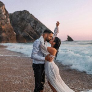 How to plan a beach wedding in Zanzibar 5 A couple embraces on a beach during their wedding at sunset, waves crashing around.