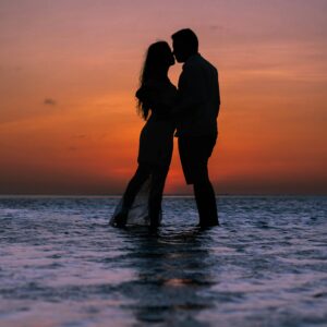 How to plan a beach wedding in Zanzibar 2 Silhouette of a couple kissing at the beach during a vibrant sunset, creating a romantic ambiance.