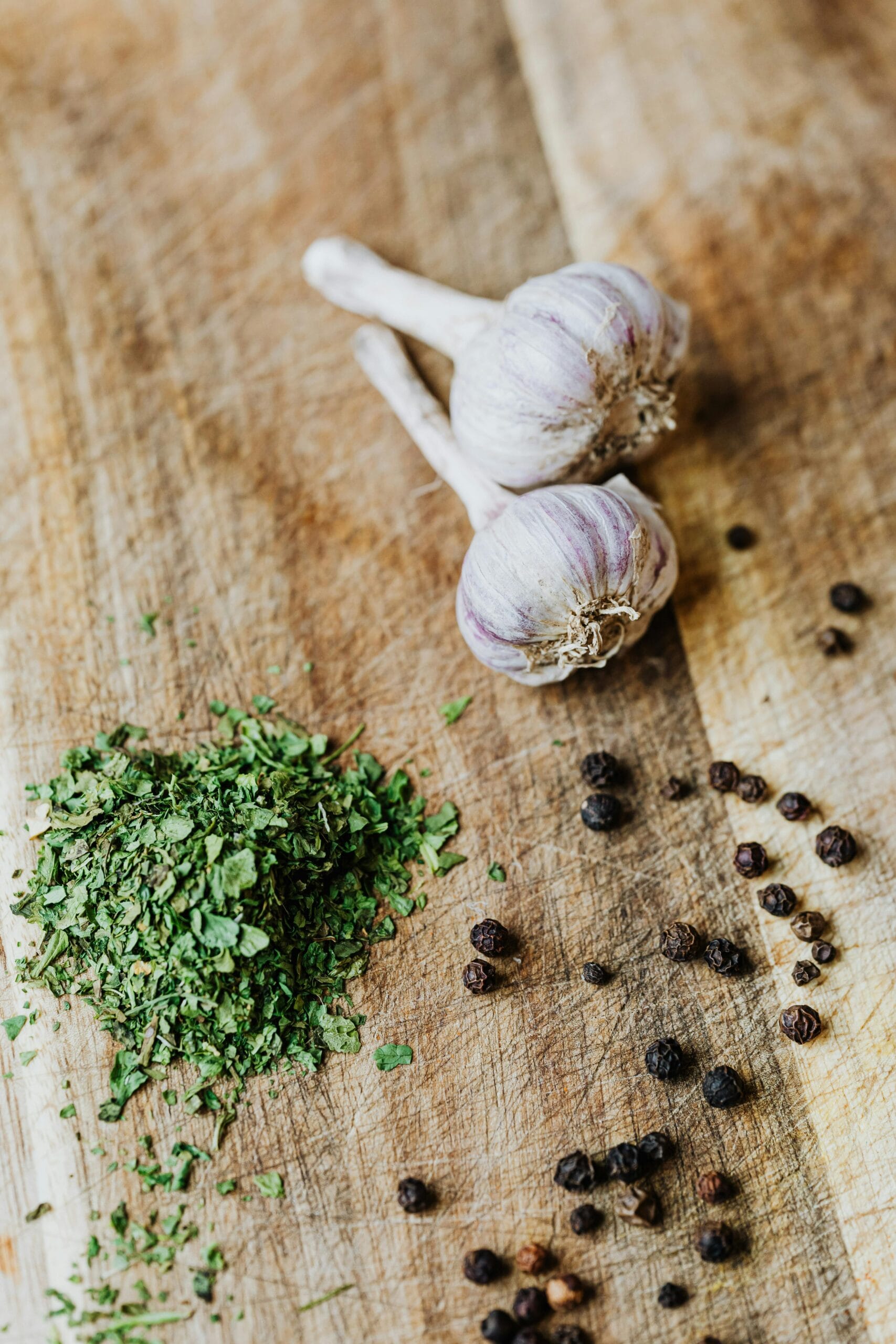How to Explore Zanzibar’s Spice Farms: A Sensory Journey Through the Island’s Rich Flavors 5 Top-down view of garlic cloves, herbs, and peppercorns on a rustic wooden cutting board.