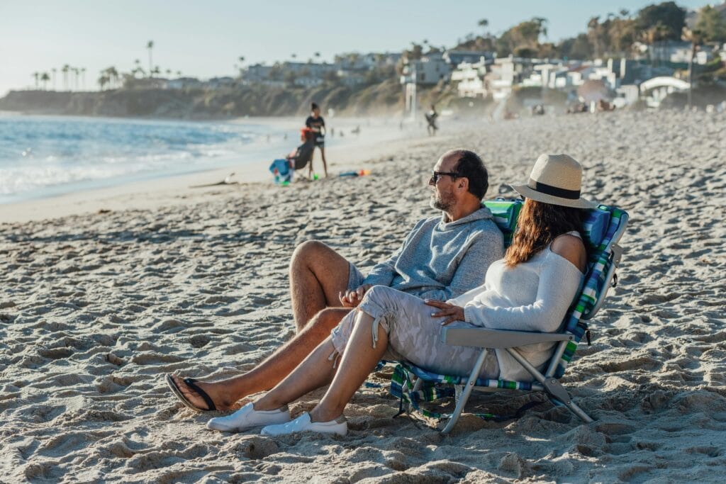 A senior couple relaxes in beach chairs enjoying a sunny seaside day during vacation.