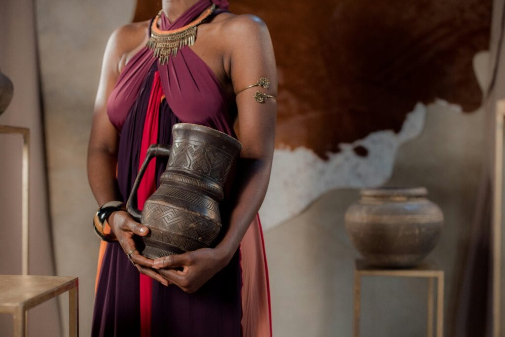 A woman in a flowing dress holds an intricately designed ceramic vase, embodying traditional elegance.