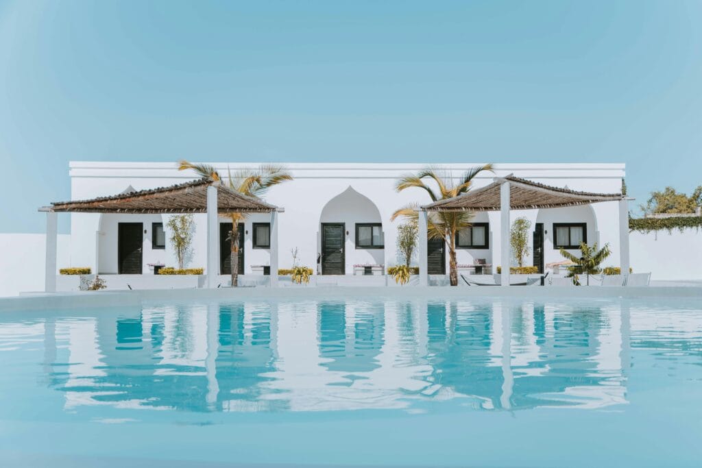 Elegant white villa in Zanzibar featuring a stunning swimming pool and palm trees under a blue sky.