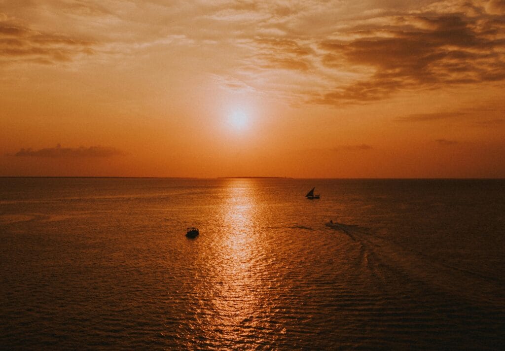 The best viewpoints for sunset in Zanzibar 10 A tranquil view of sunset with boats on the horizon over the ocean in Zanzibar.
