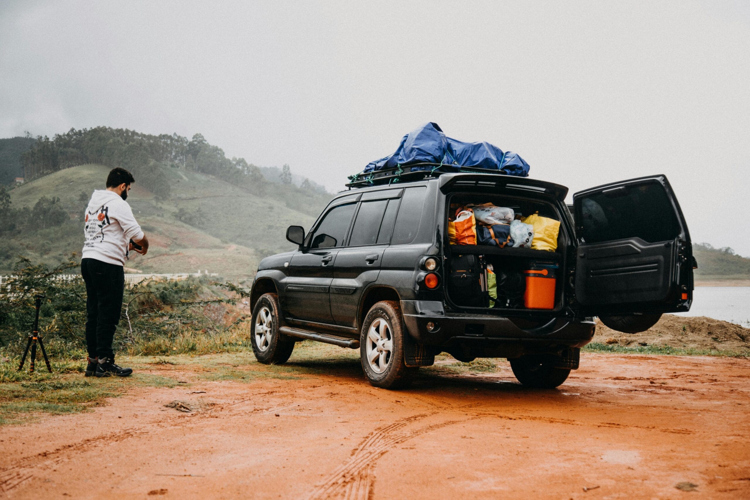 Man prepares for a foggy countryside adventure trip with a packed SUV.