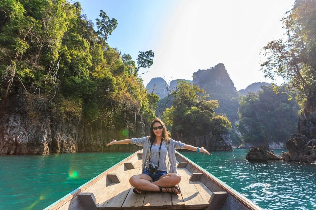 Tips for Staying Cool on Safari: Beat the Heat While Exploring Africa 7 Asian woman relishing a serene boat journey through the lush karst landscape of Thailand's Khlong Sok.