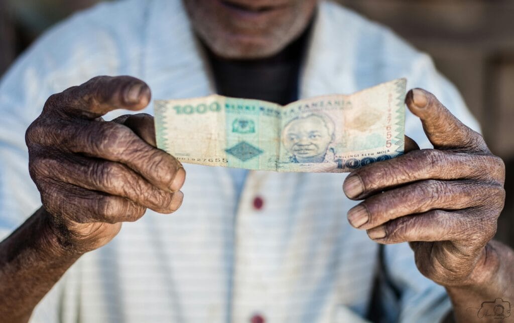 Navigating currency exchange in Zanzibar 10 Close-up of elderly hands holding a Tanzanian Shilling. A portrait representing economy and heritage.