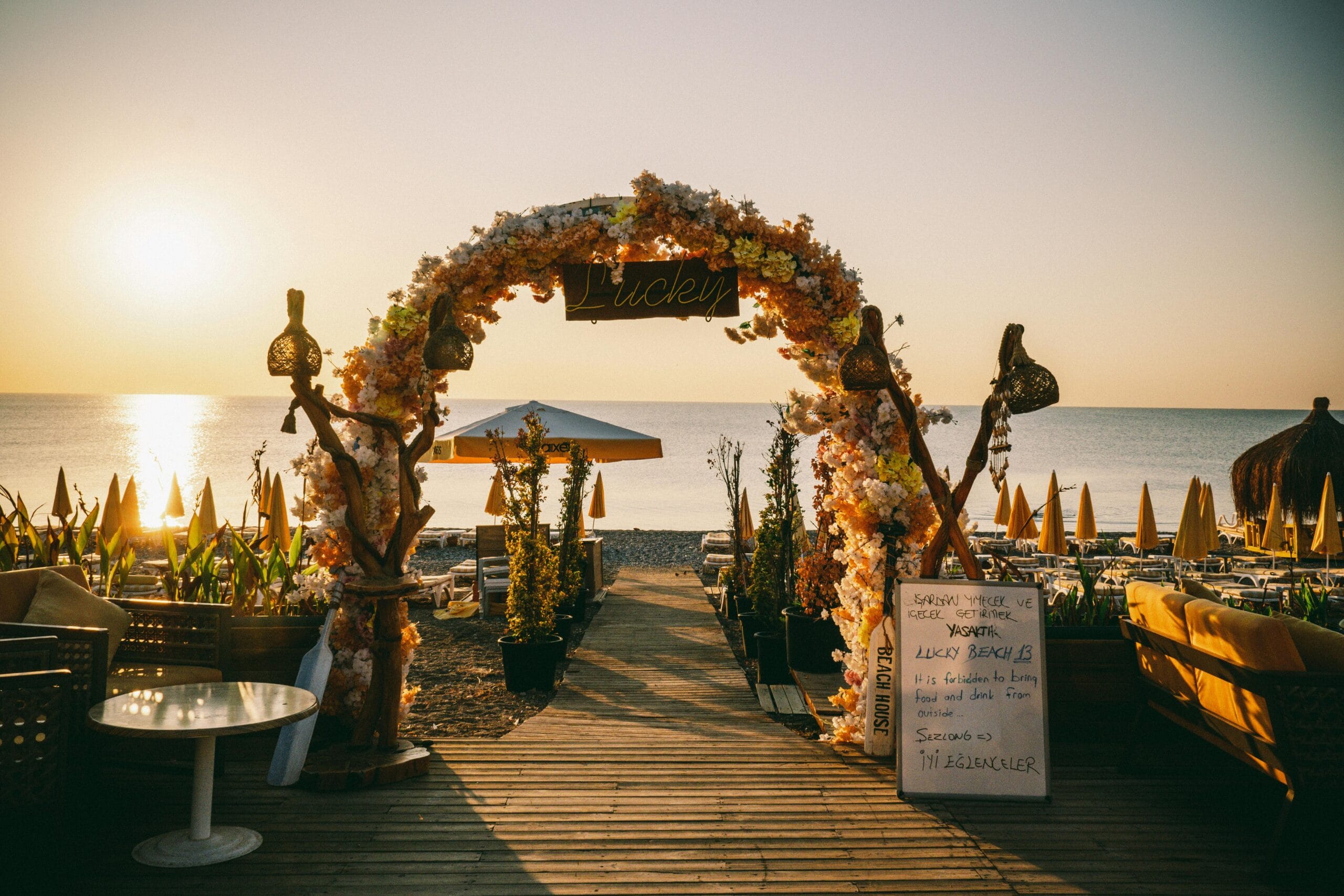 Beautiful floral archway on a beach at sunset, perfect for weddings and events.