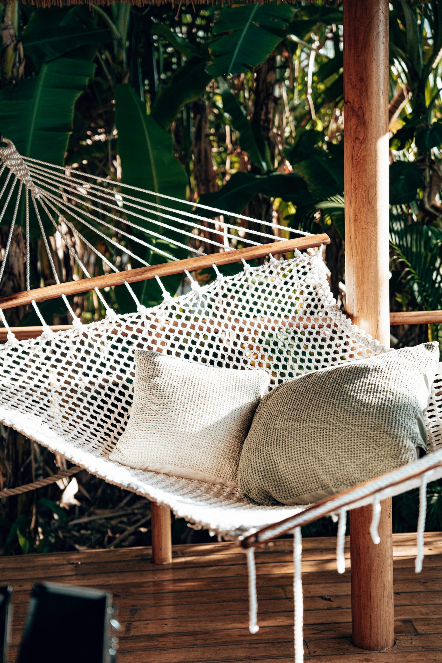 Planning a multi-destination trip including Zanzibar 2 A cozy hammock with pillows in a tropical setting on a wooden verandah surrounded by lush greenery in Tanzania.