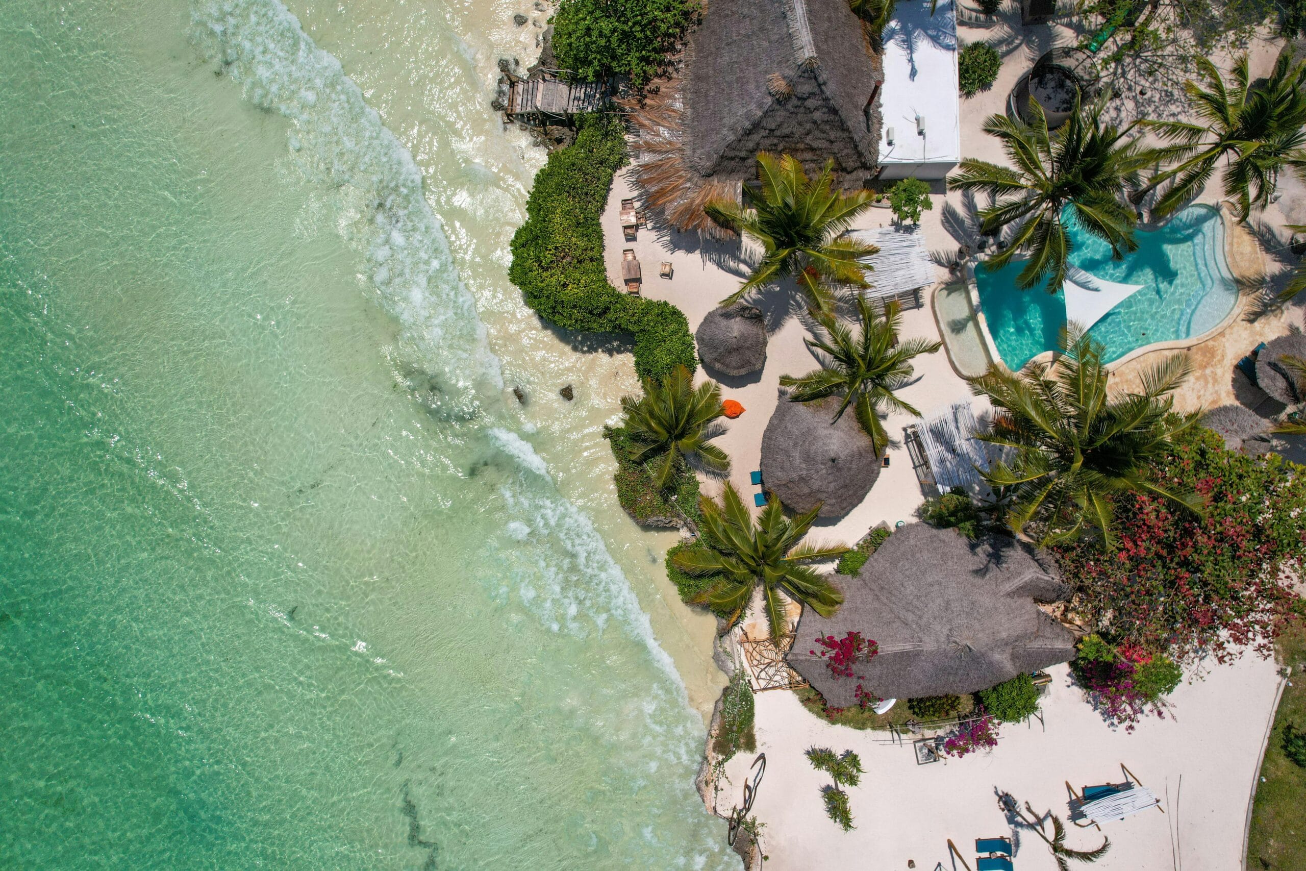 Breathtaking aerial view of a tropical beach resort in Zanzibar with turquoise waters and palm trees.