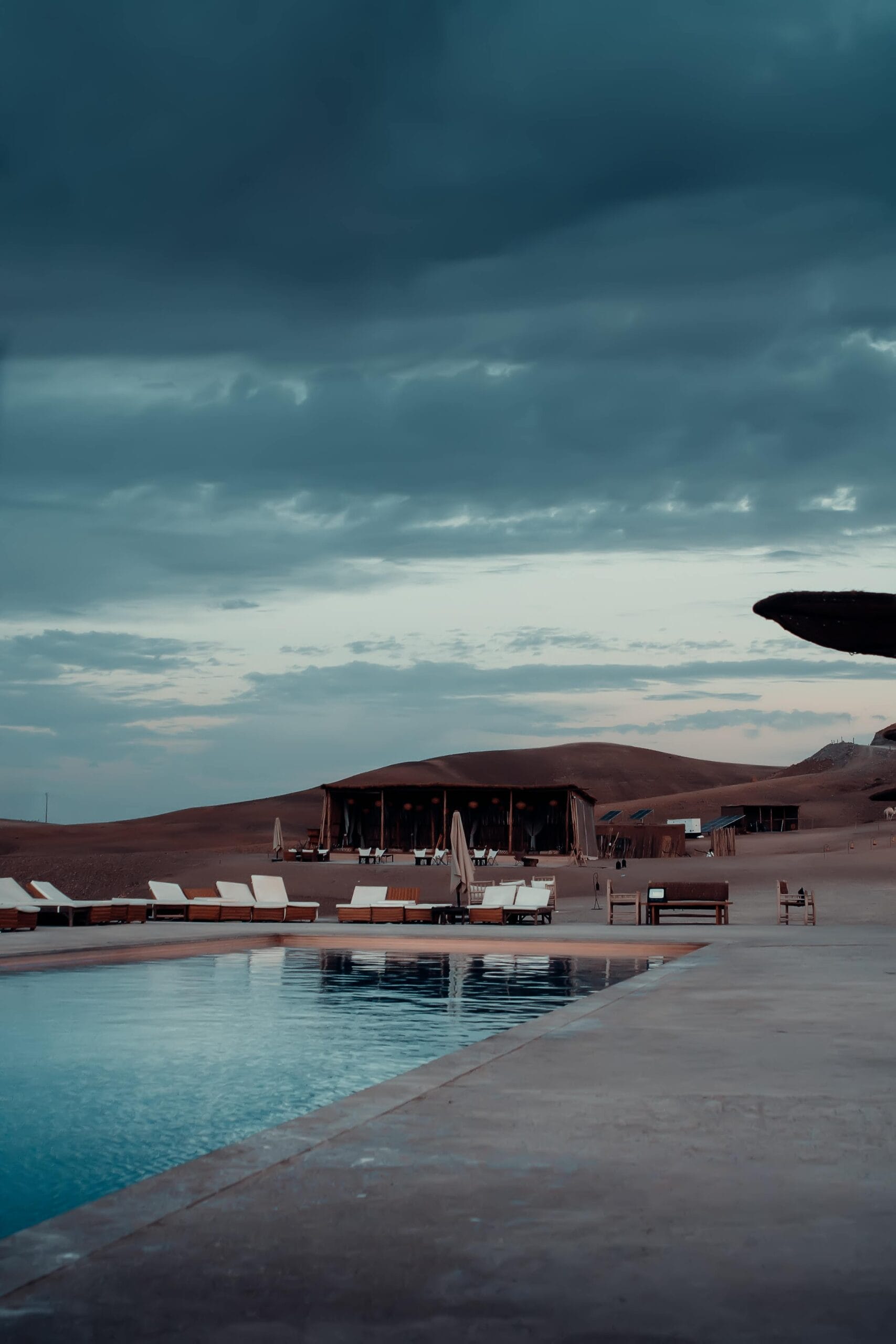 7-Day Family-Friendly Safari with Exclusive Lodges 1 Tranquil desert scene with a luxury poolside view at a glamping resort in Agafay, Morocco.