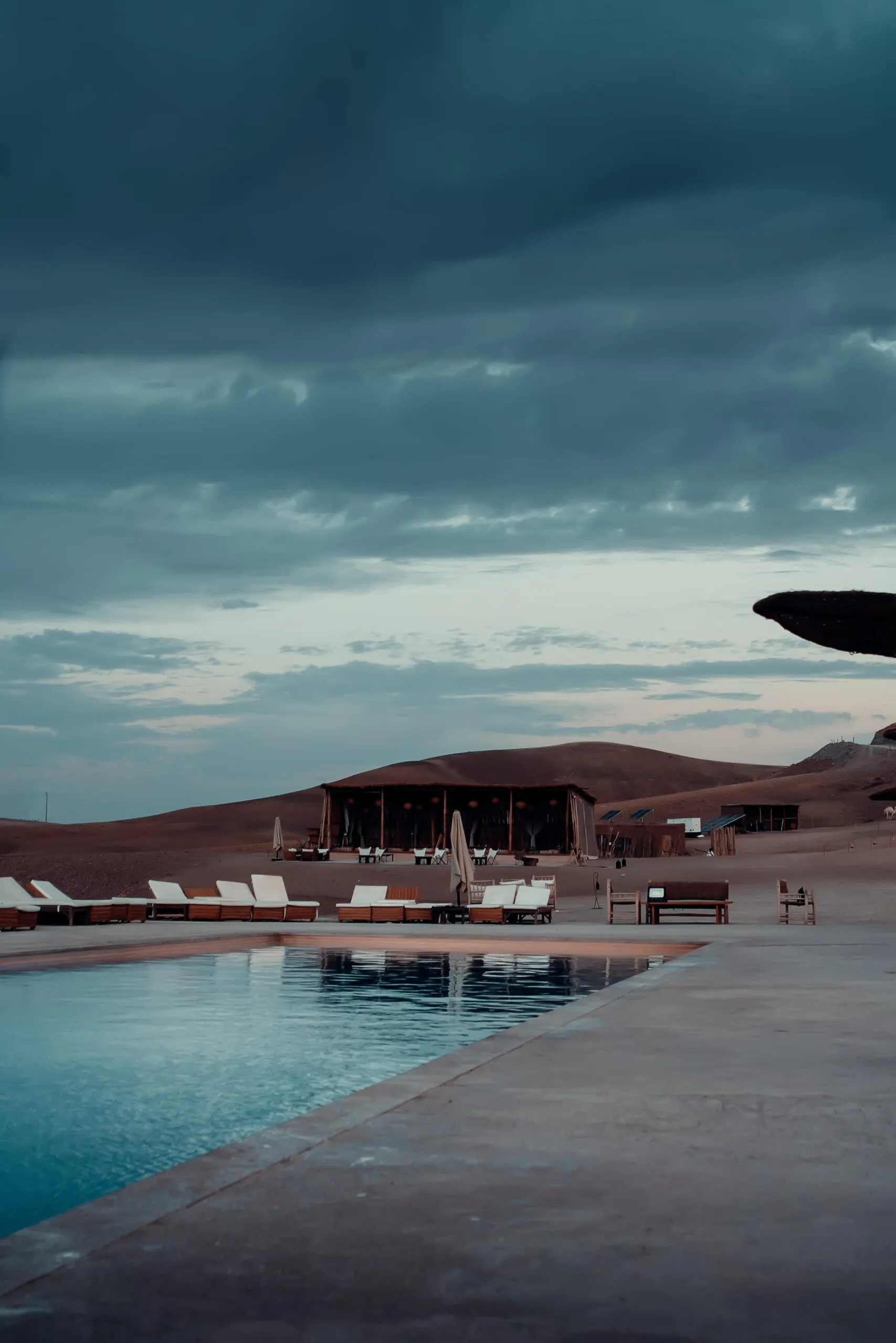 7-Day Family-Friendly Safari with Exclusive Lodges 1 Tranquil desert scene with a luxury poolside view at a glamping resort in Agafay, Morocco.