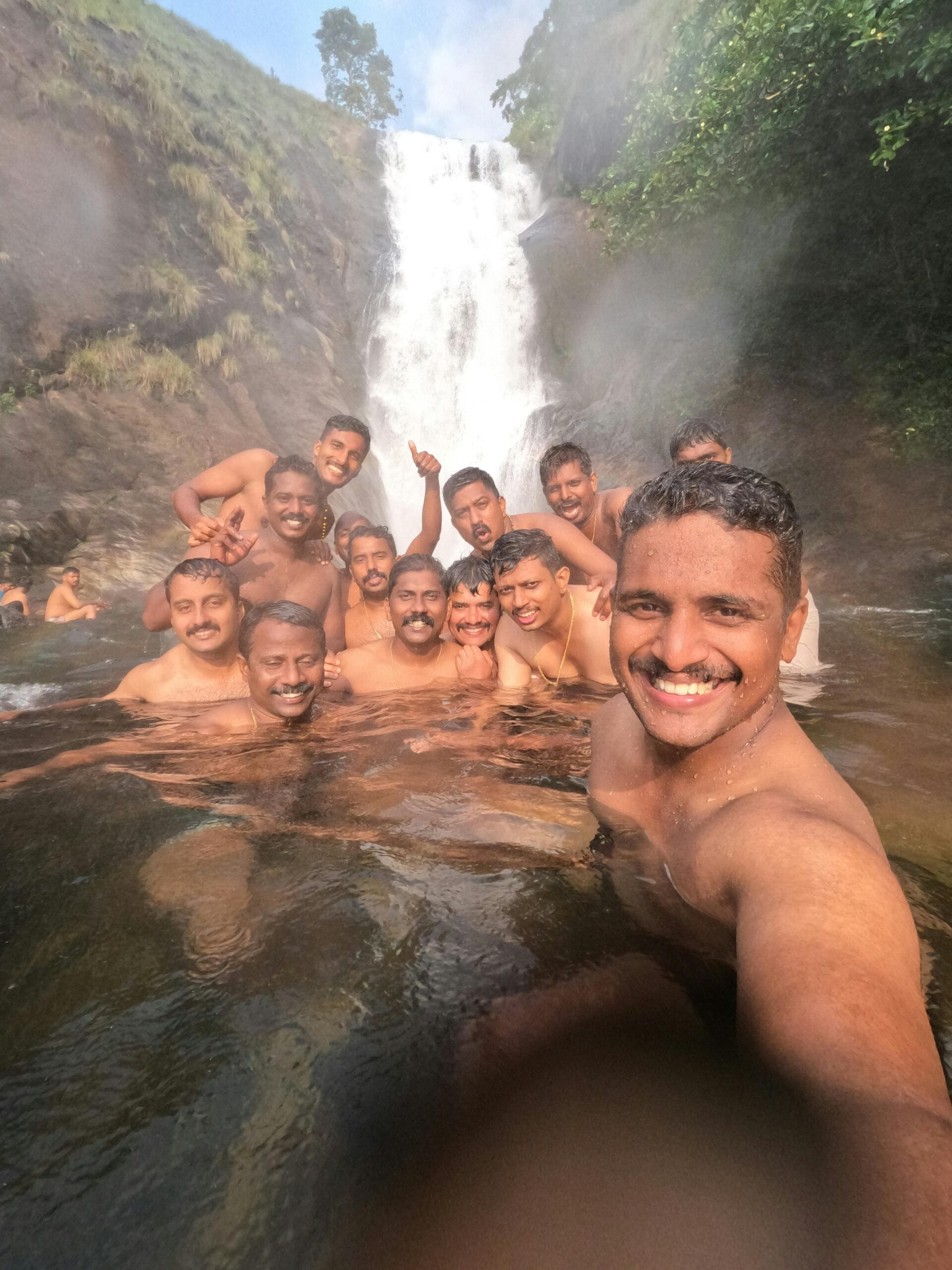 Expert Tips for a Memorable Safari Experience 1 A group of friends having fun swimming near a waterfall at Poonjar Vadakkekara, Kerala.