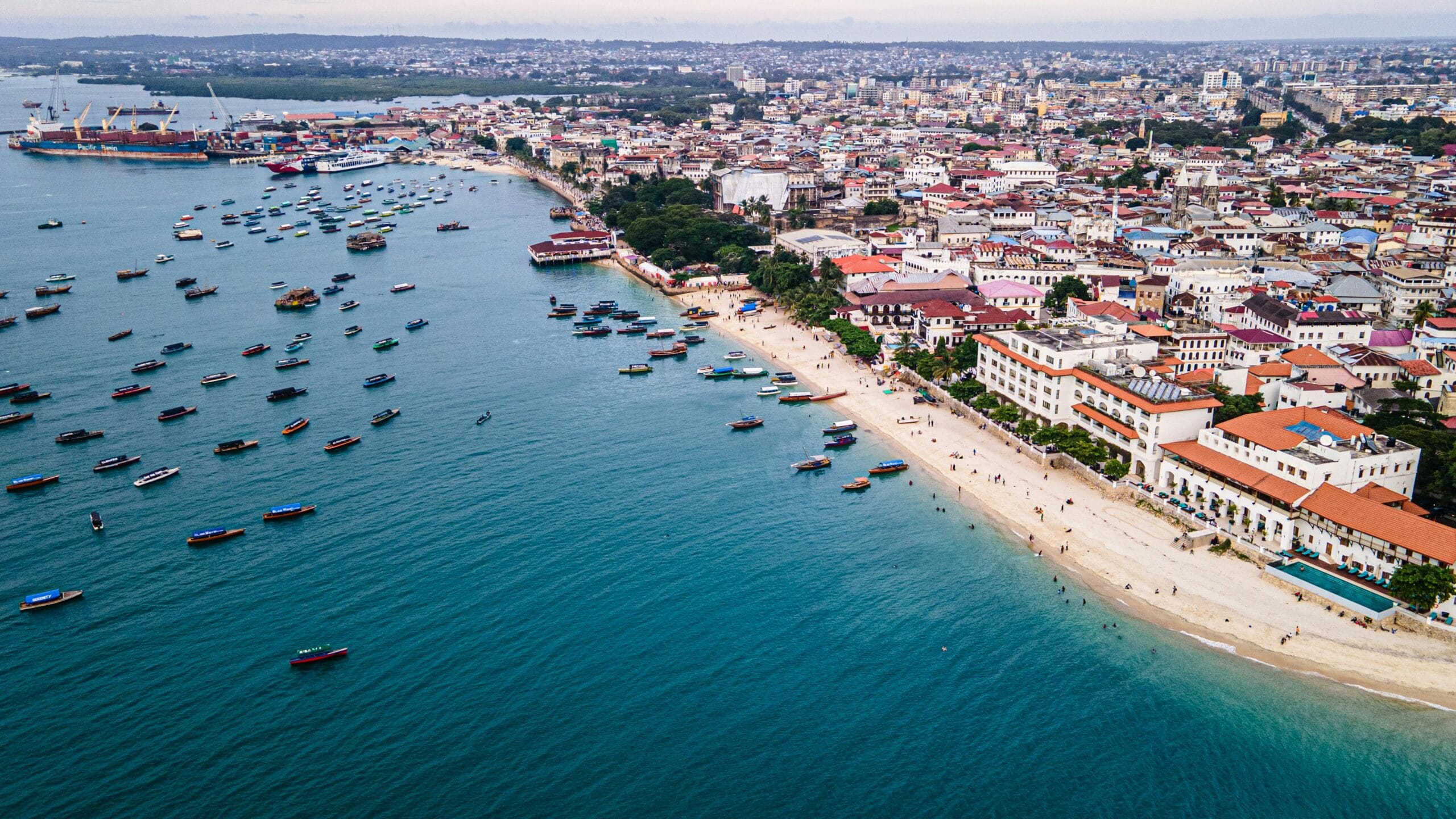 7 Days Zanzibar Island & Safari 11 Stunning aerial view of Zanzibar Stone Town's coastline with boats and vibrant cityscape.