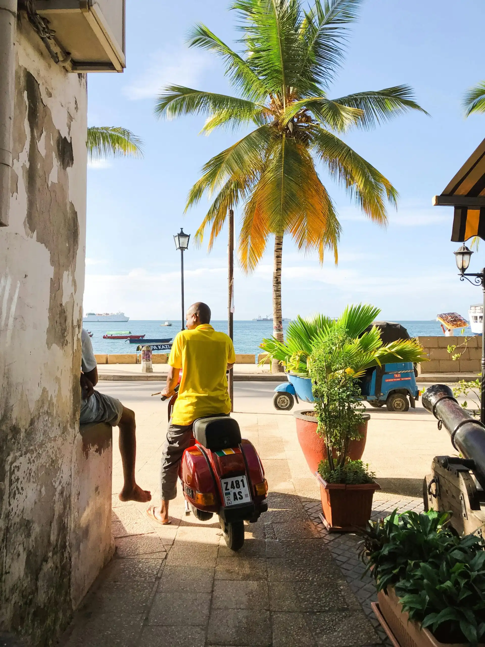 How to Get Around Zanzibar: Easy Transportation Tips for Travelers 1 A vibrant scene of a man on a scooter by the beach in Zanzibar, Tanzania.