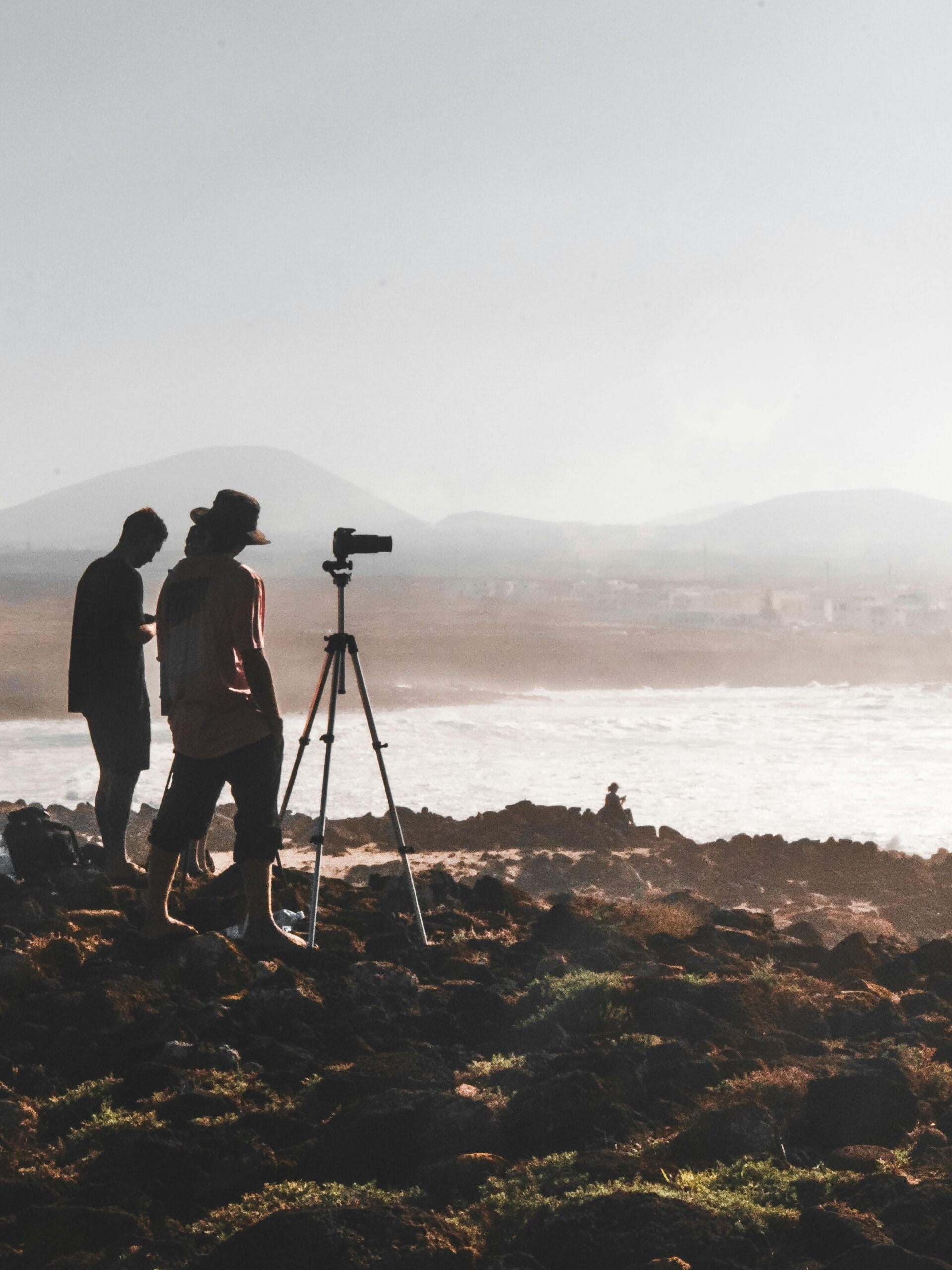 Exclusive Safaris for Photographers: Capture the Beauty of Tanzania Like Never Before 2 Two photographers with a tripod capture the scenic seascape at sunset in Lanzarote, Spain.