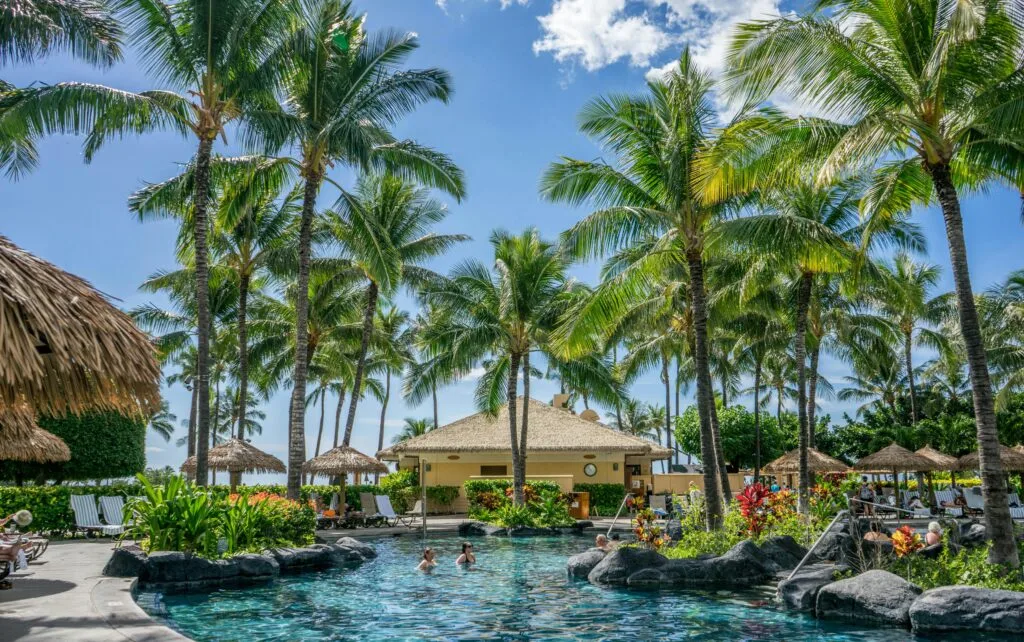 Best family resorts in Zanzibar 7 Relaxing tropical resort scene with palm trees, swimming pool, and clear blue sky.