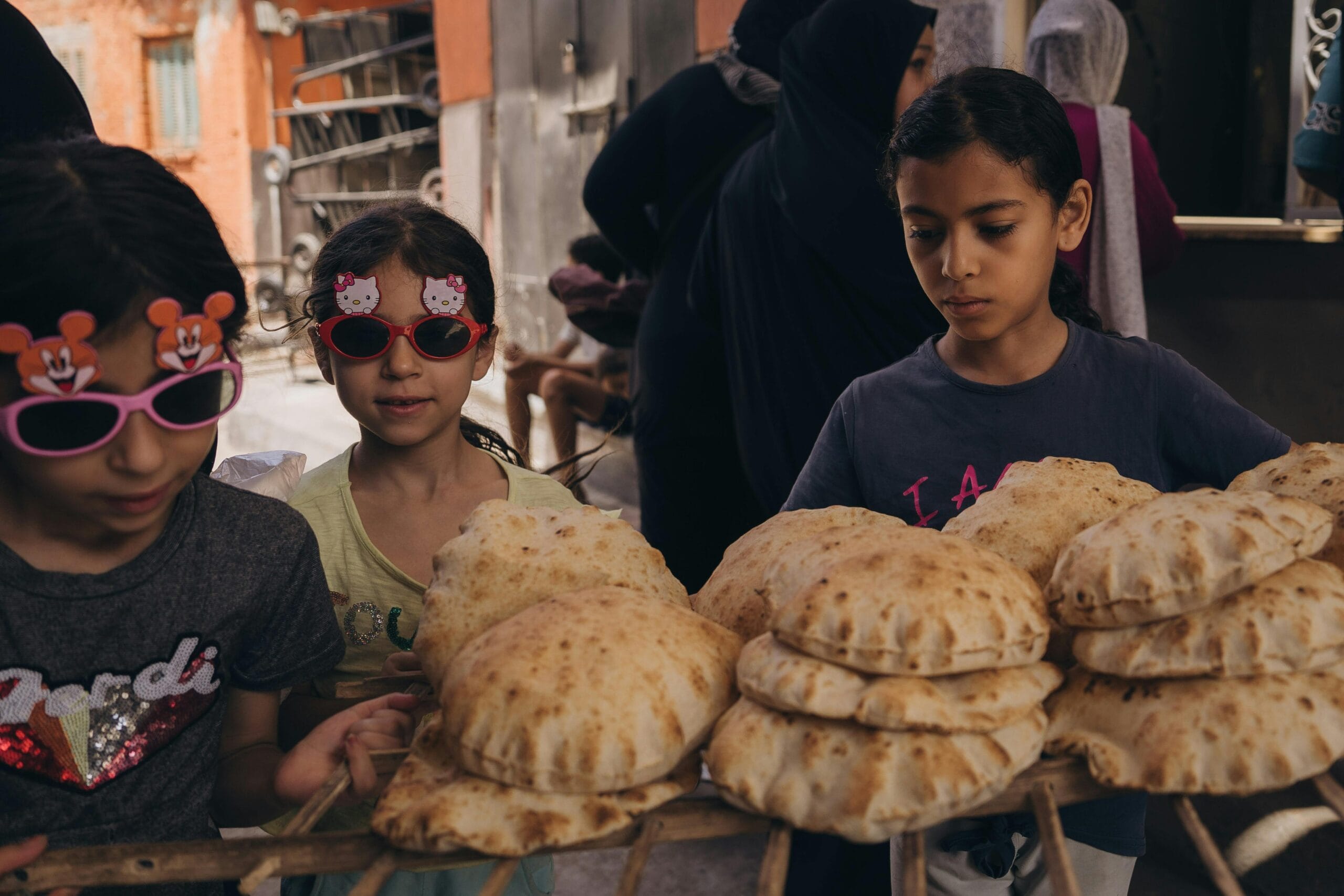 Children in Alexandria exploring a local bakery with fresh bread, reflecting Egyptian street culture.