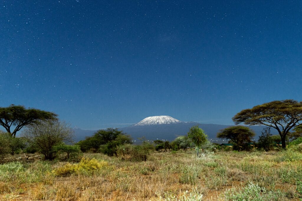 Top 10 Tanzania National Parks to Explore in 2025 | Ultimate Safari Guide 19 A breathtaking view of Mount Kilimanjaro framed by a clear starry night sky from Kajiado County, Kenya.