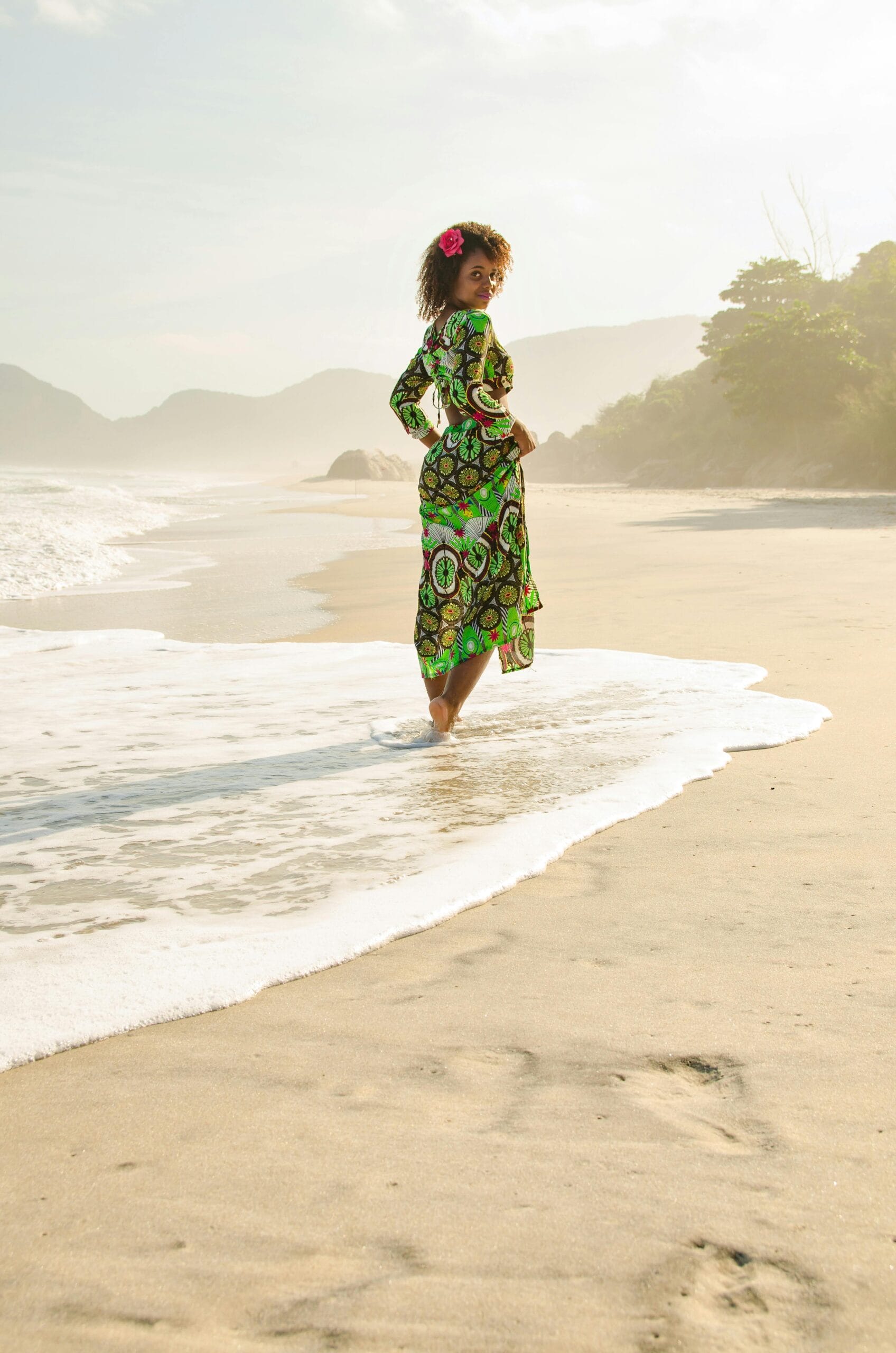 Tips for solo travel in Zanzibar 1 A woman in a colorful dress enjoys a sunny day at the beach, walking along the shore.