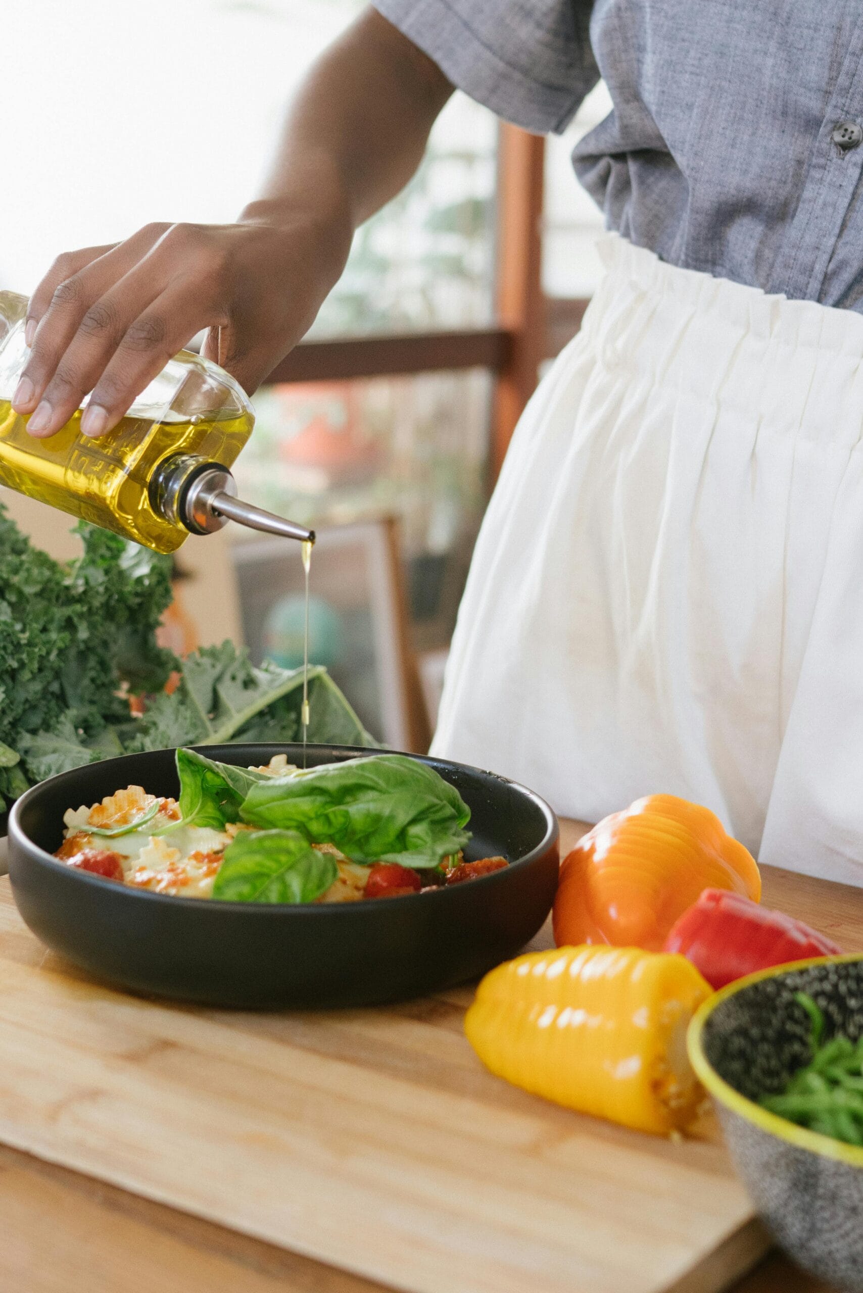 Tanzanian Cooking Classes on Safari: A Culinary Adventure in the Heart of Africa 1 Person drizzles olive oil over fresh vegetable salad on a wooden cutting board.