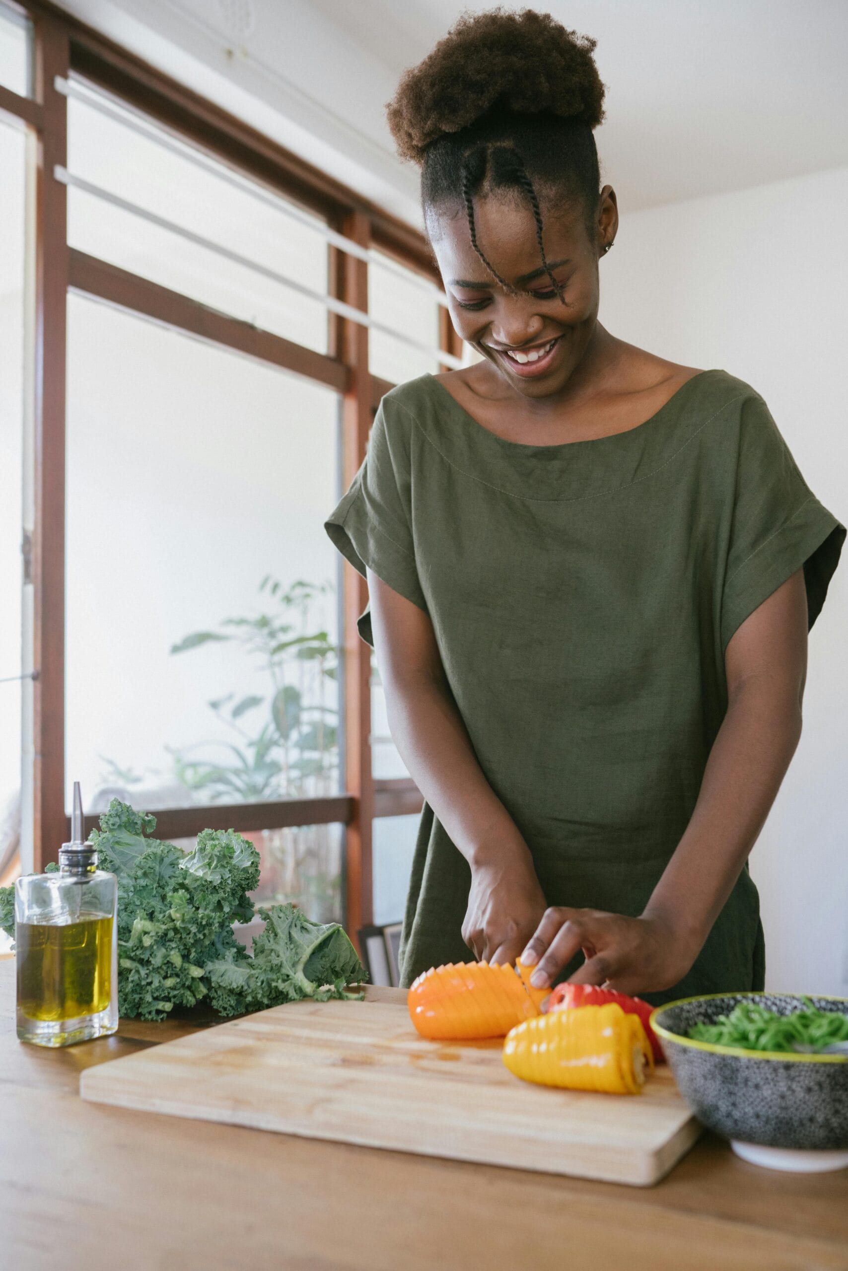 Traditional Foods to Try in Tanzania: A Taste of Local Flavors 2 Smiling woman in kitchen slicing bell peppers, promoting healthy eating and joy in food preparation.