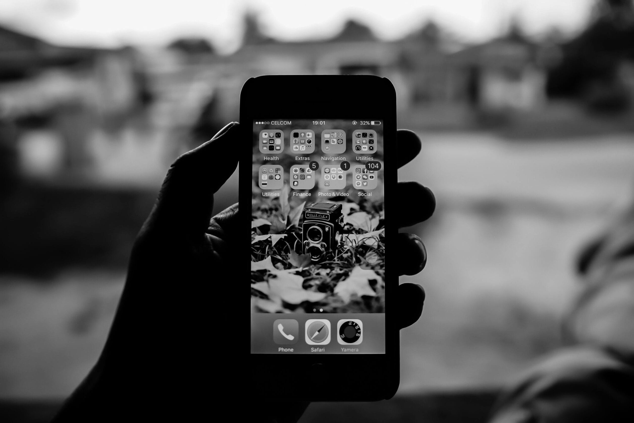 Black and white image of a smartphone showcasing a vintage camera wallpaper, emphasizing technology and nostalgia.