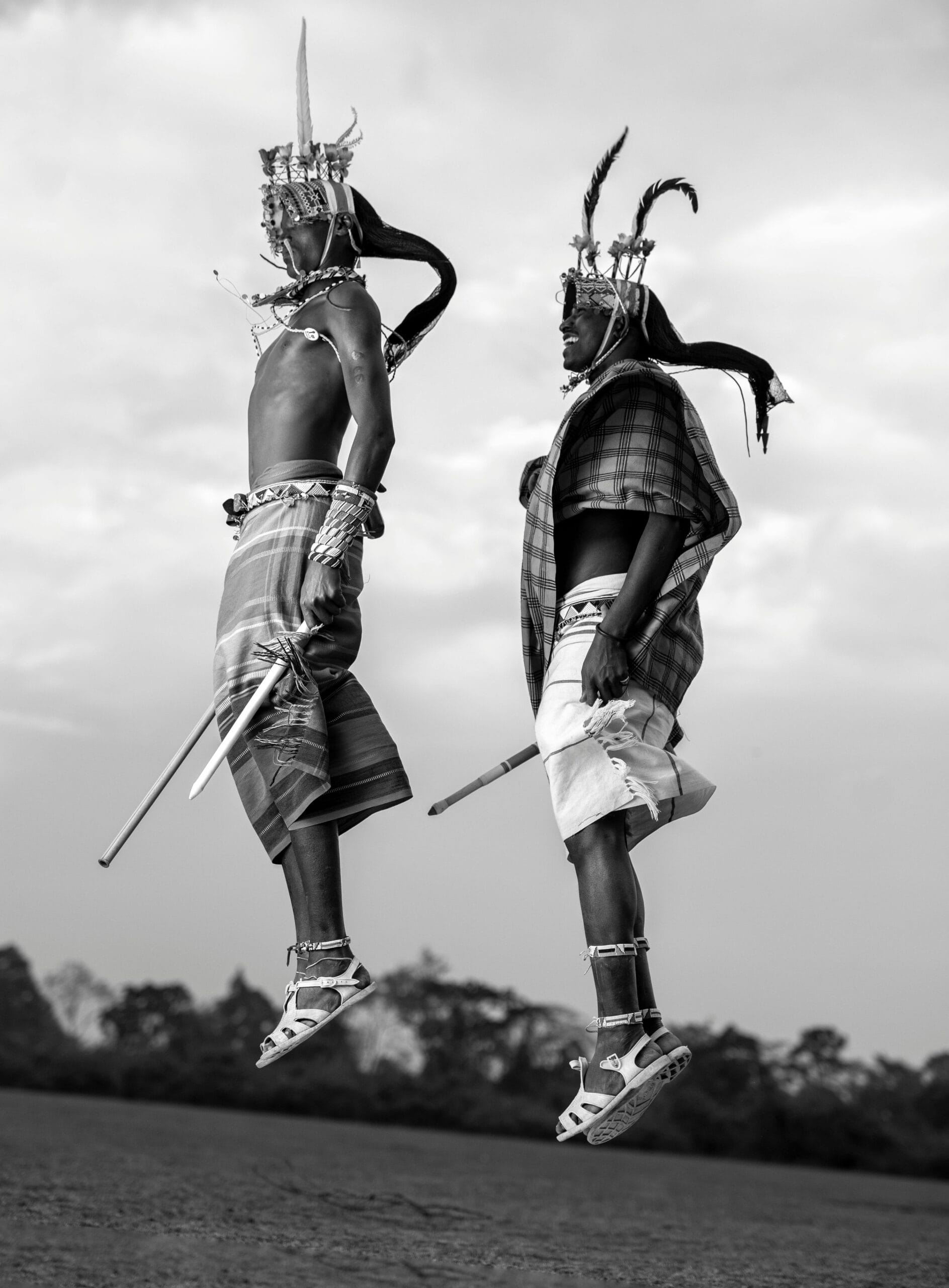 1-Day Cultural and Wildlife Safari at Ngorongoro Crater 1 Two men in traditional attire jump mid-air showcasing cultural dance with headdresses in Kenya.