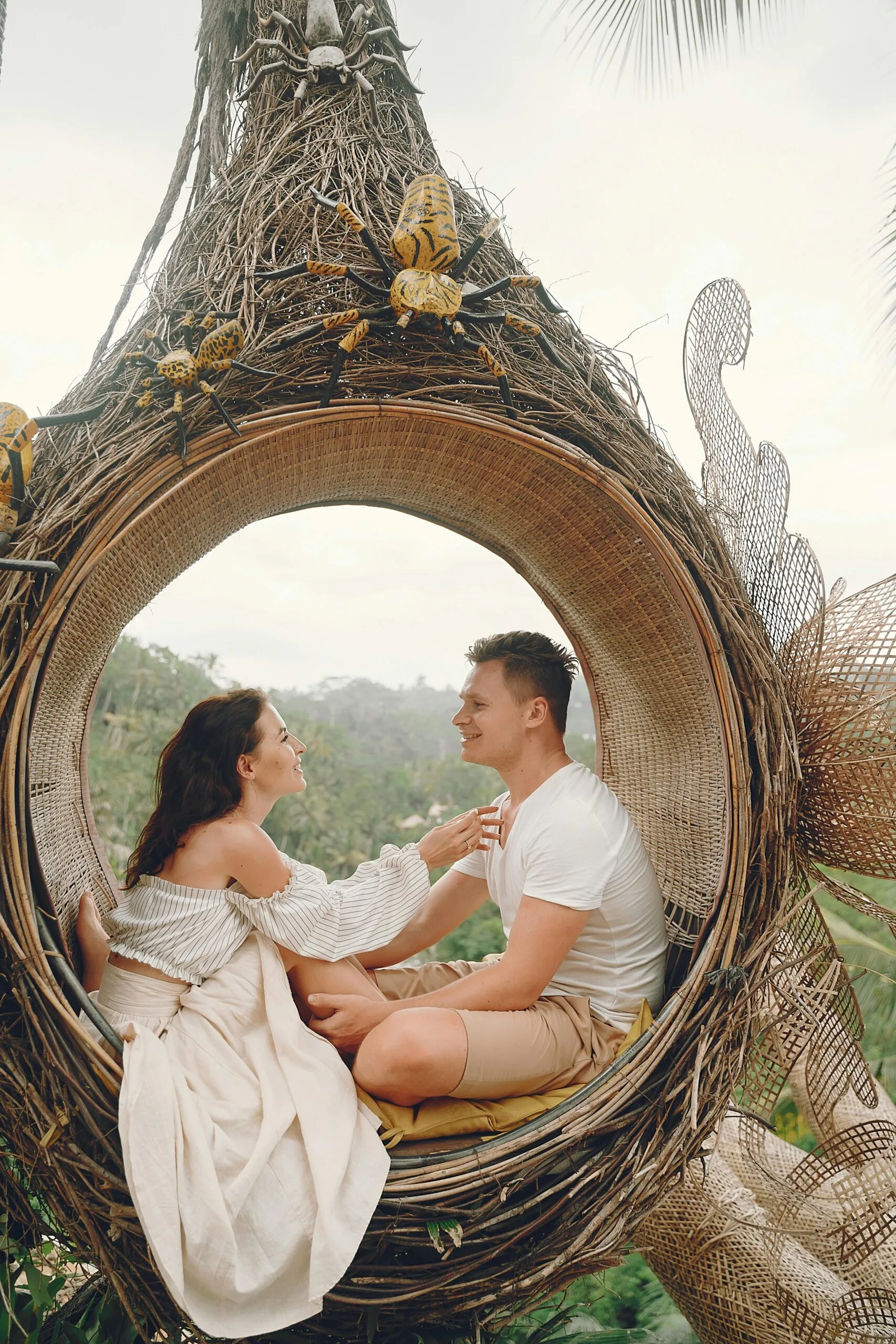 Special Offers for Group Safaris: Explore Tanzania Together 1 Side view full body barefoot content young couple in white casual clothes sitting in wicker hanging swing and looking at each other with love while spending honeymoon in tropical resort
