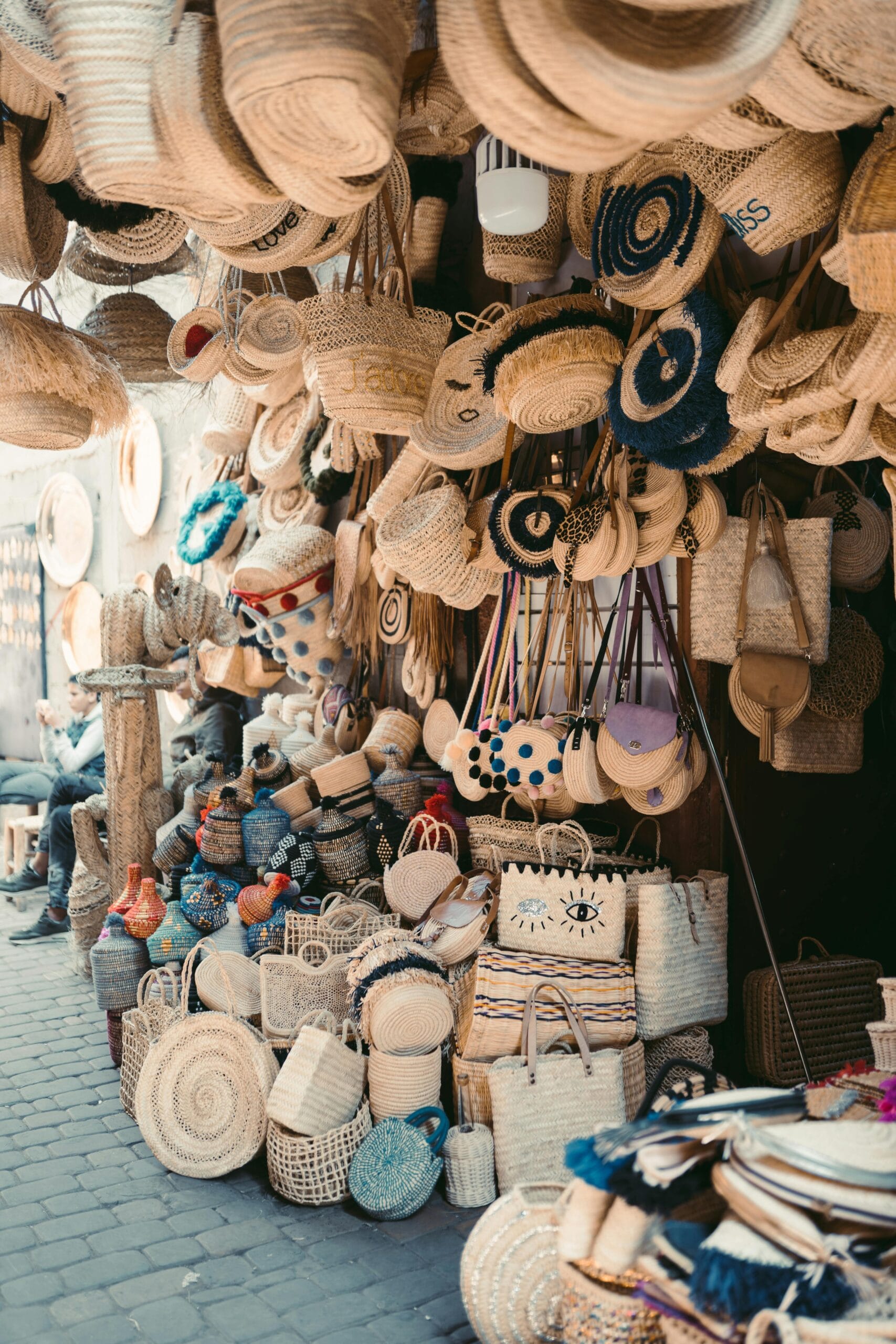 Supporting Local Crafts in Tanzania: A Journey Through Art, Culture, and Community 1 Vibrant display of handmade woven bags and hats in a Marrakesh street market.