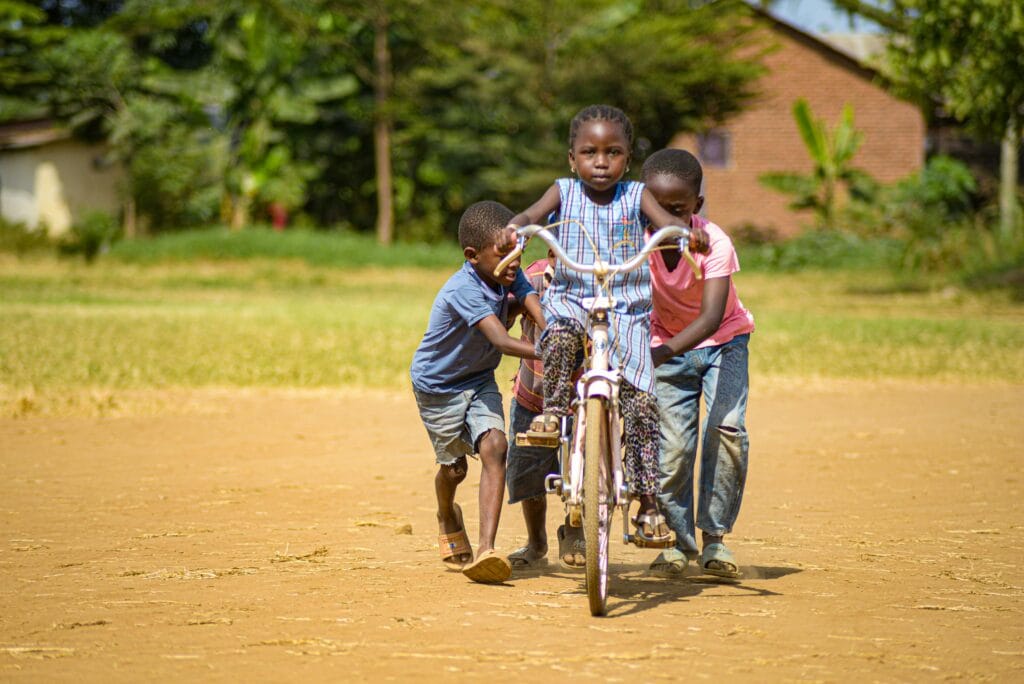 Cultural Insights: Meet Local Communities on Safari 4 Three children playfully push a bicycle on a sunny day in Morogoro, Tanzania.