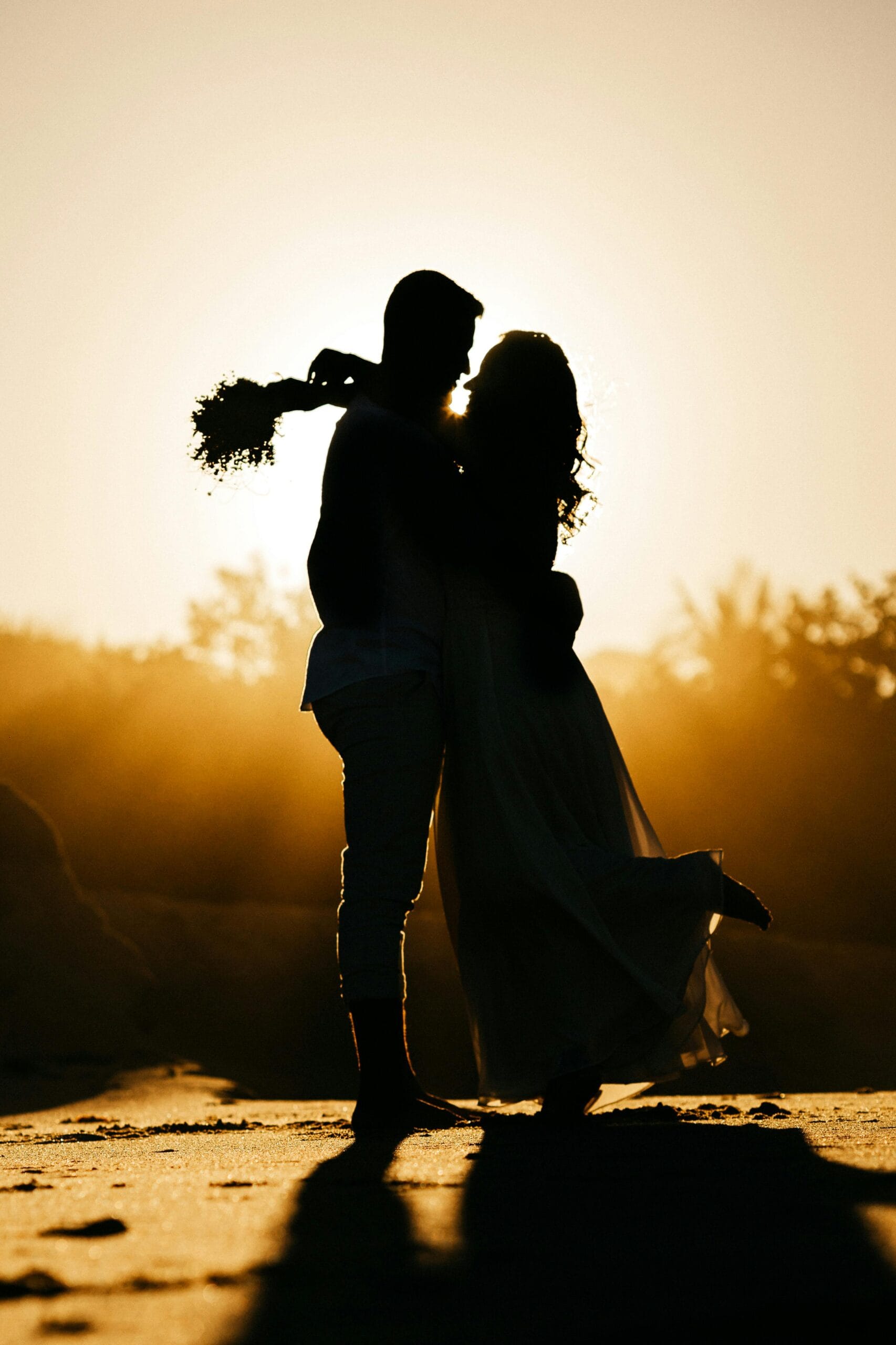 Safari Tours for Honeymooners: A Romantic Adventure in Tanzania 2 Side view silhouettes of happy young couple hugging each other while relaxing on sandy beach during date at sunset