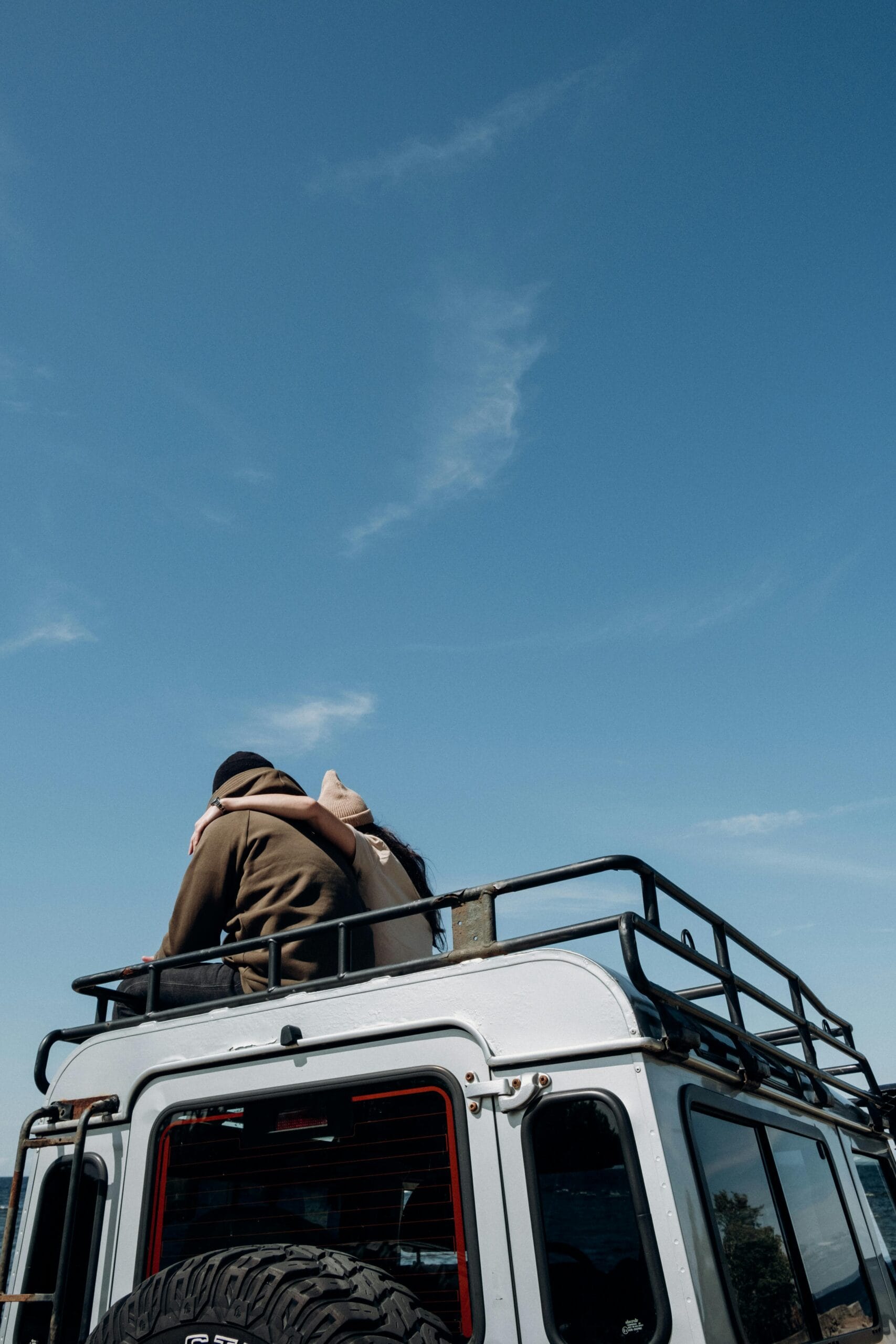 5-Day Luxury Safari with Private Jeep and Guide 1 Romantic couple sitting on SUV roof enjoying a sunny day outdoors with clear blue sky.
