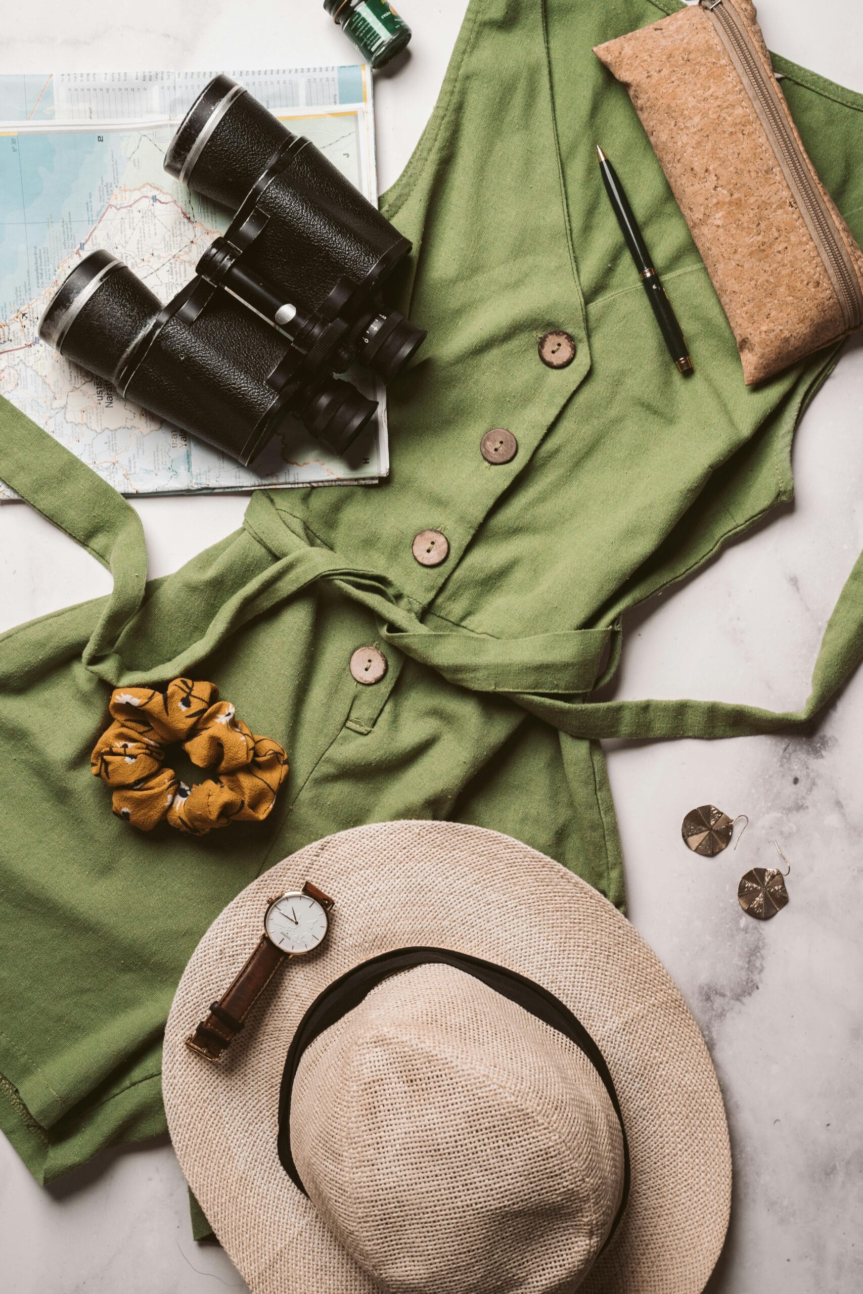 What to pack for a Tanzanian safari 1 Flat lay of a travel outfit with binoculars, hat, and map for an adventure theme.