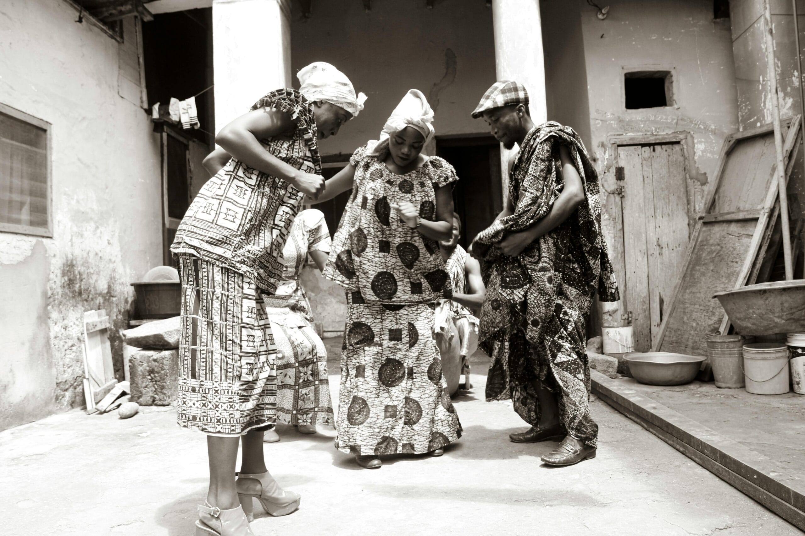 Joyful celebration of traditional Ghanaian dance by adults in vibrant attire outdoors.