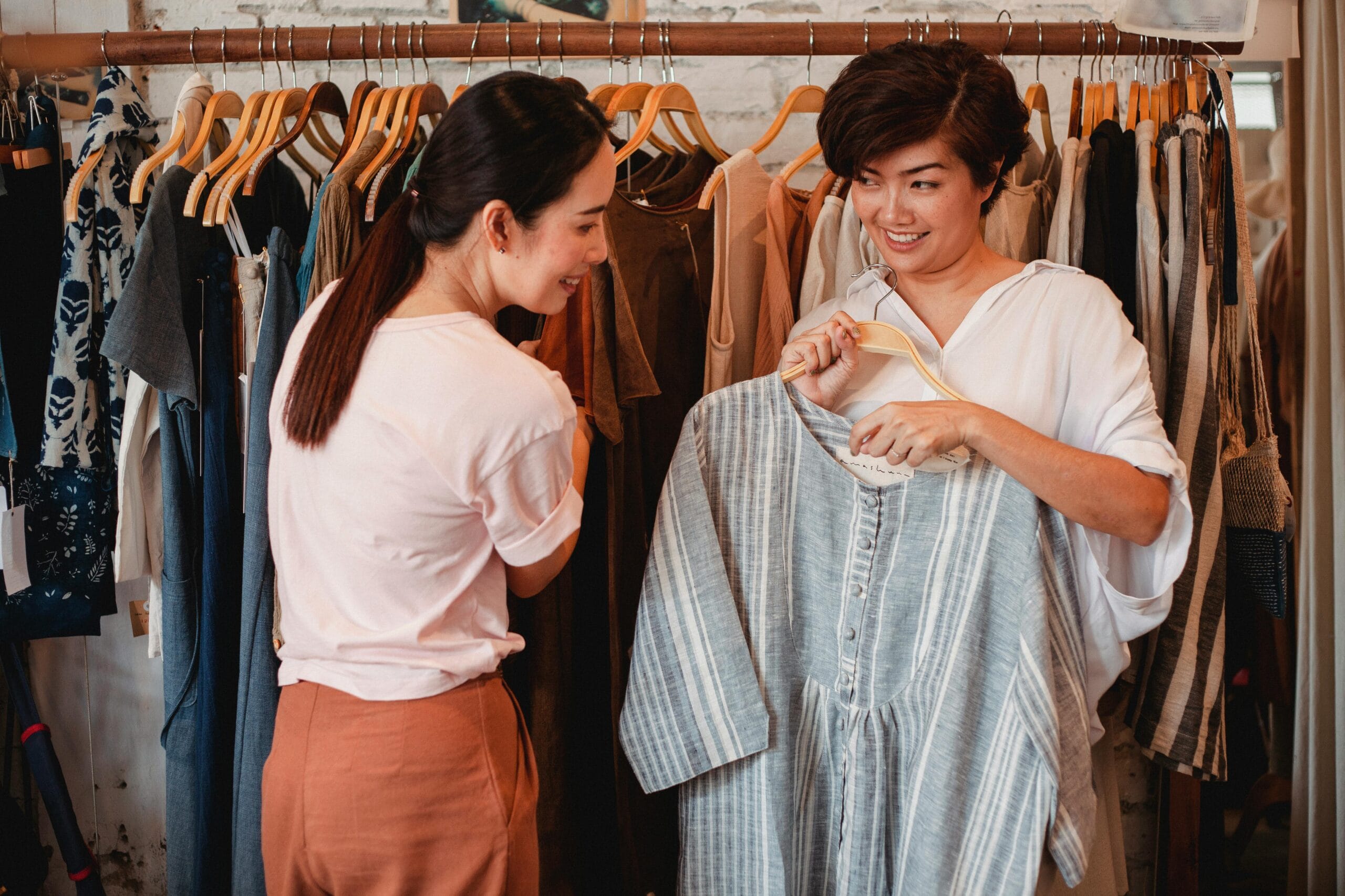 Two women enjoying shopping and trying on clothes in a trendy boutique.