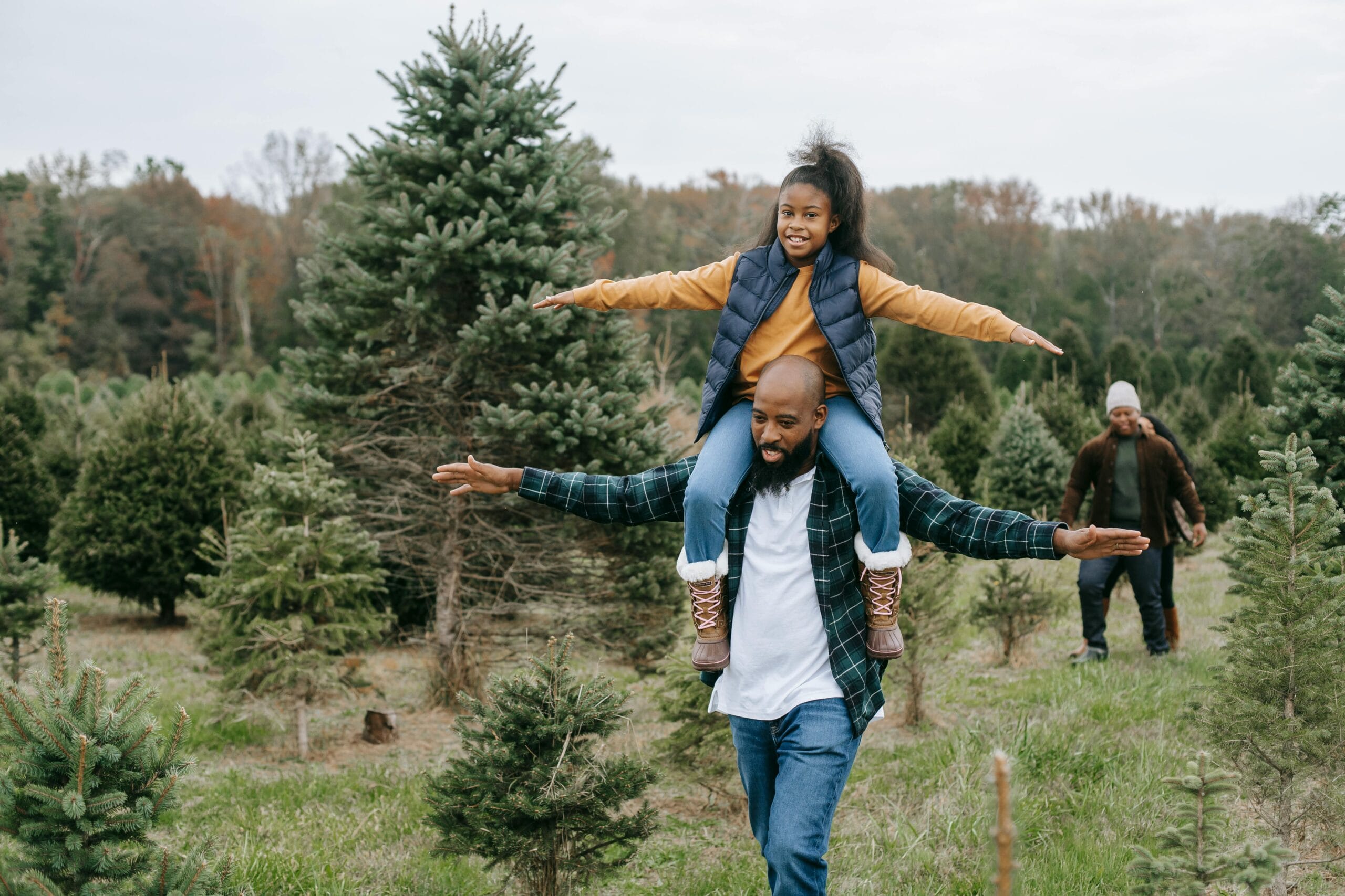 A joyful father carrying his daughter on shoulders in a lush forest, enjoying nature and freedom.