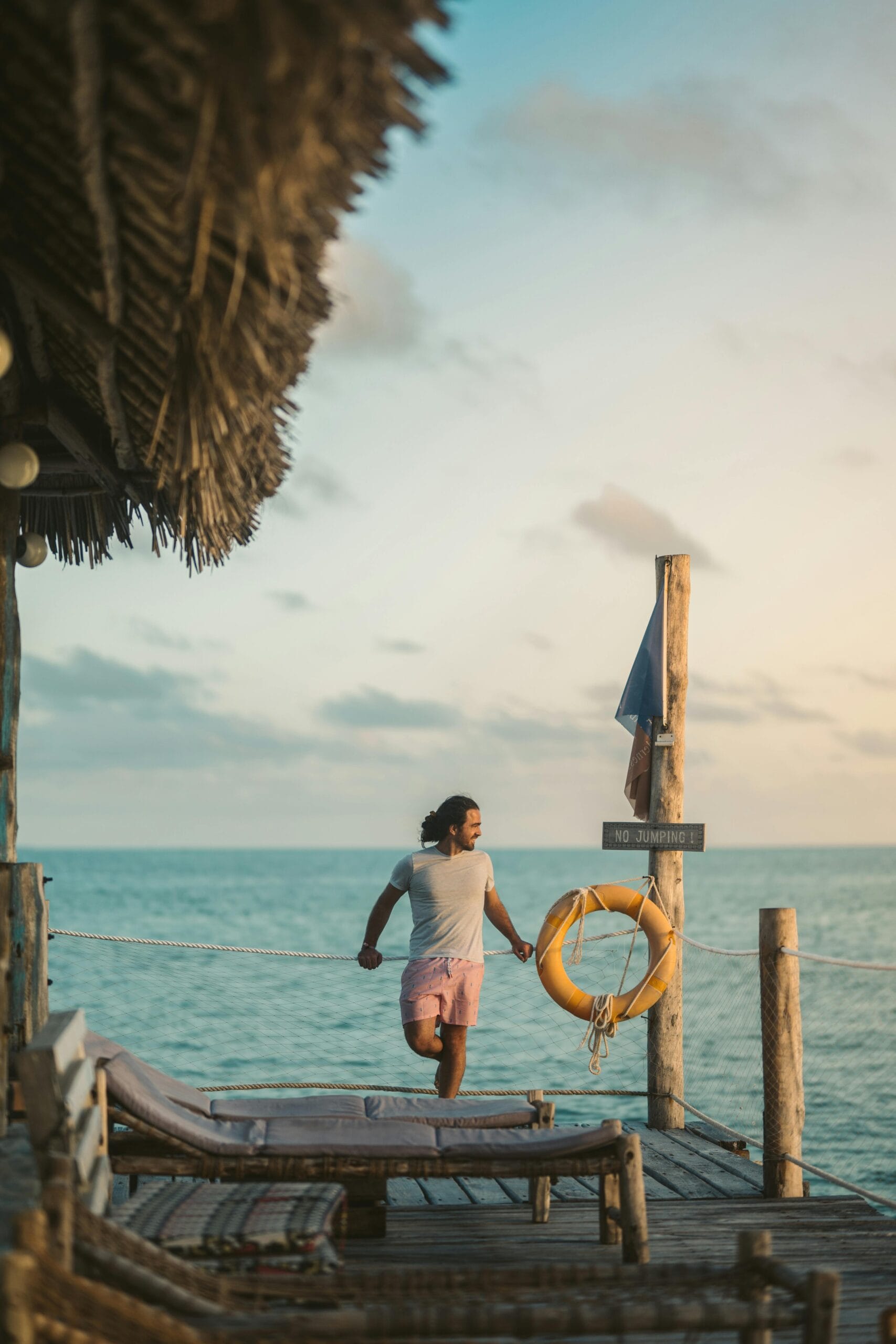 Tips for solo travel in Zanzibar 2 A man stands on a wooden platform, enjoying the scenic view of the ocean in Zanzibar at sunset.