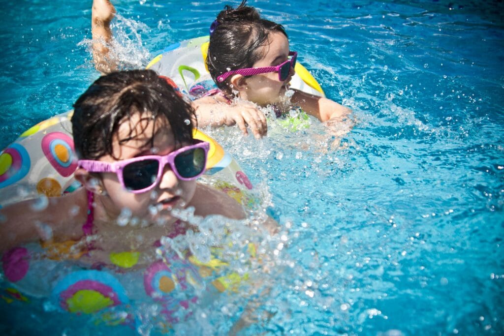 Can kids go on safari in Tanzania? 3 Two young girls enjoying a playful day in a bright blue swimming pool with colorful float rings.