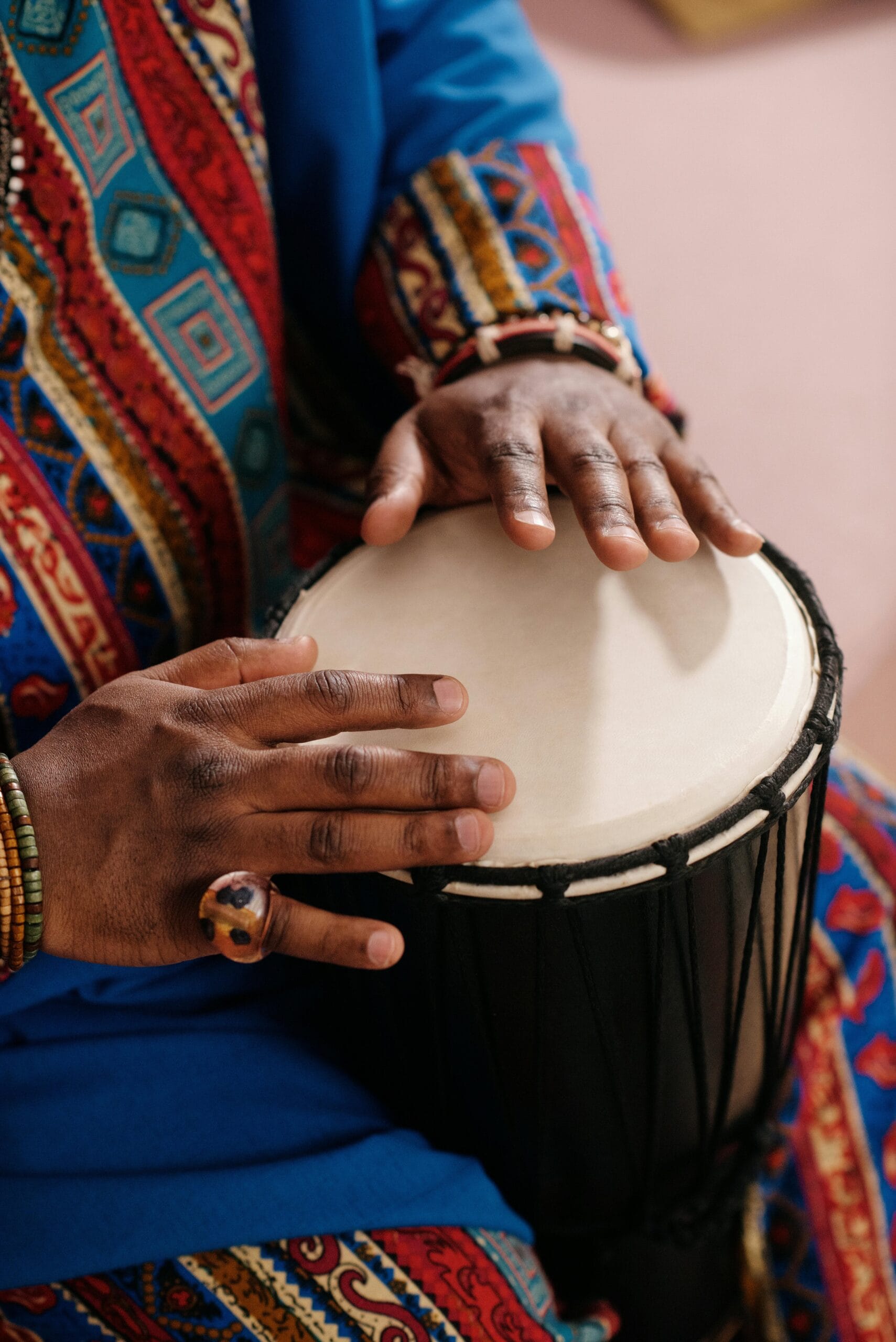 How to enjoy traditional Zanzibari music 2 Hands playing a djembe drum, wearing colorful traditional attire, highlighting cultural and musical heritage.