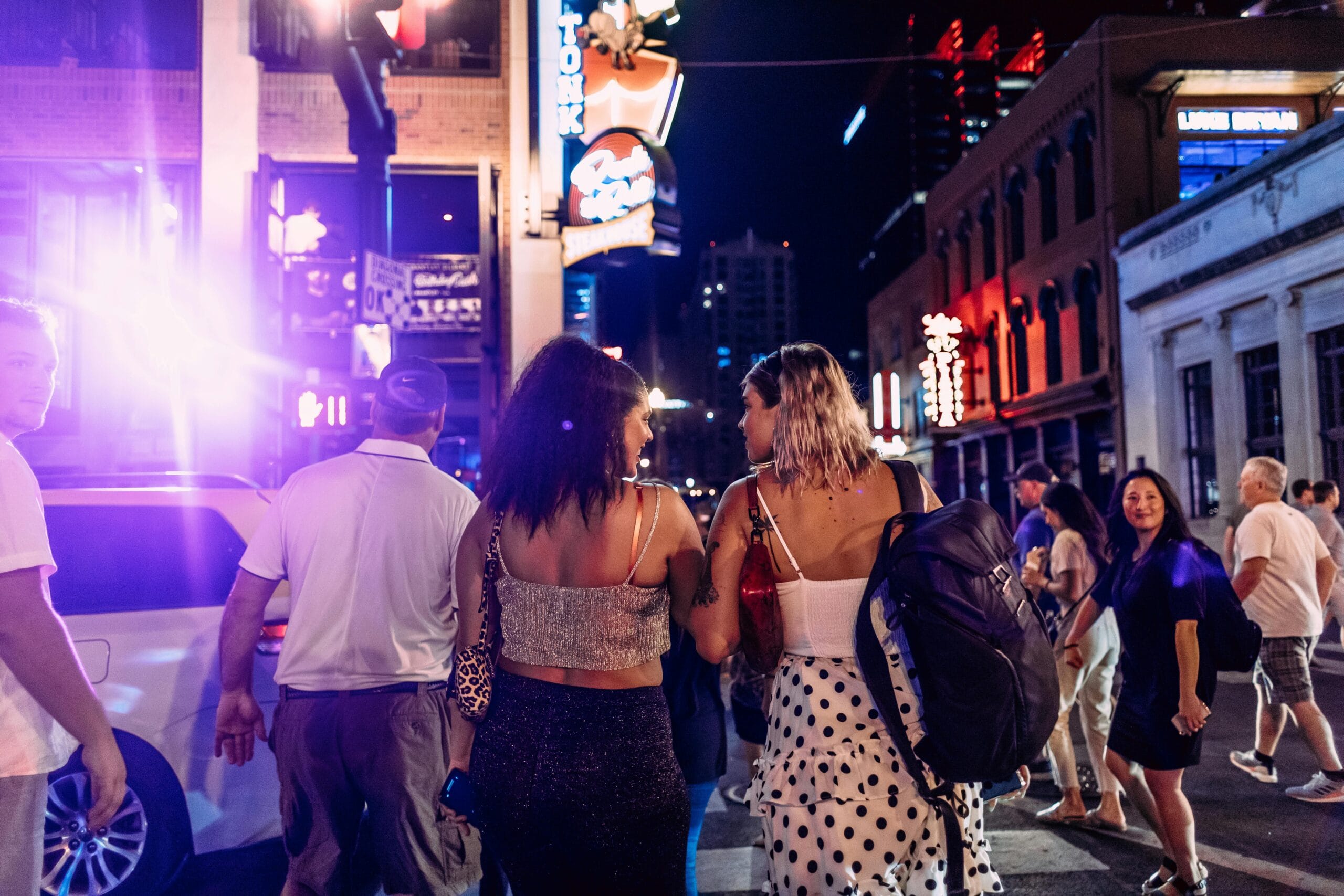 Dynamic urban street scene with pedestrians and neon signs, capturing nightlife energy.