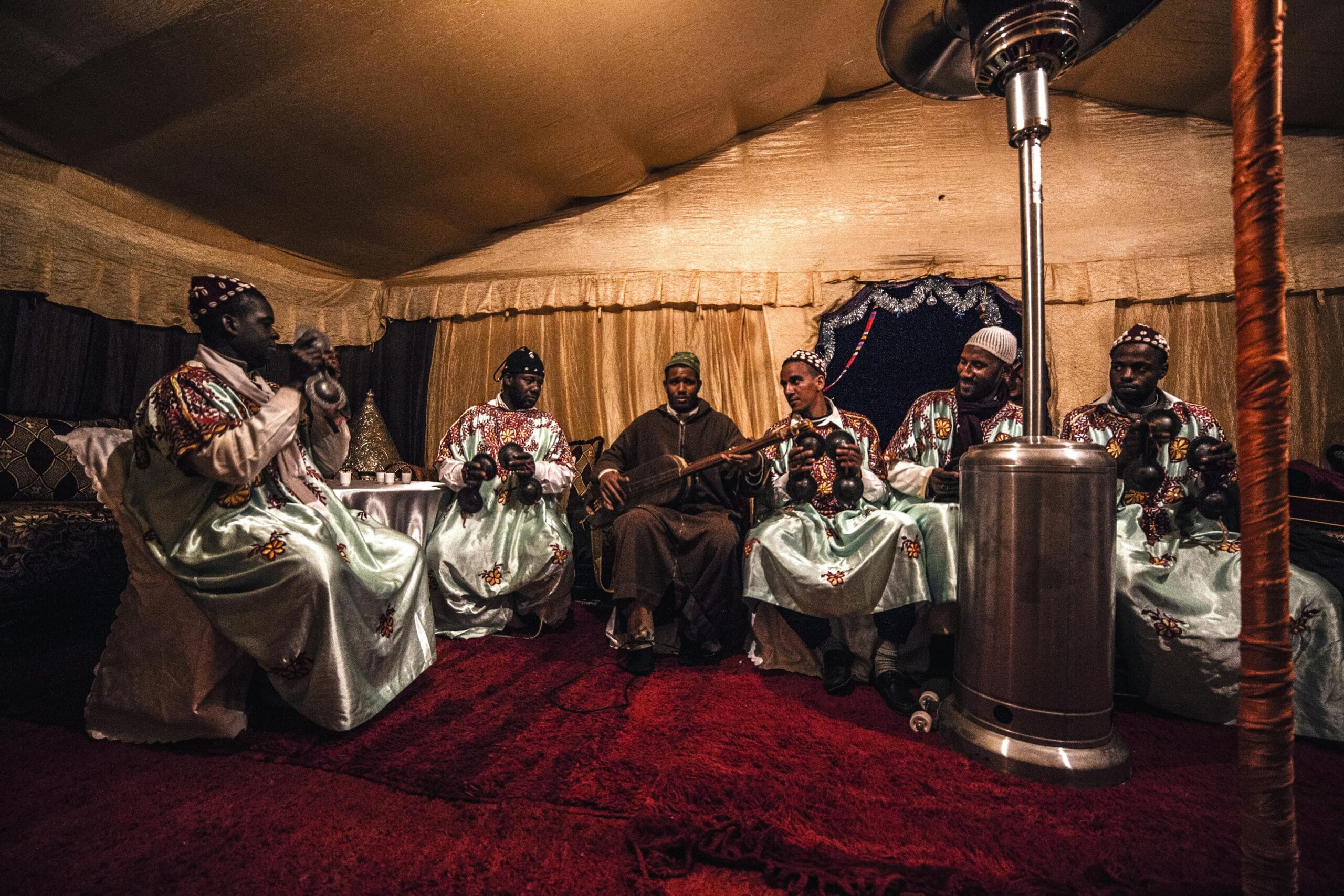 A vibrant group of African musicians performing with traditional attire and instruments inside a decorated tent.