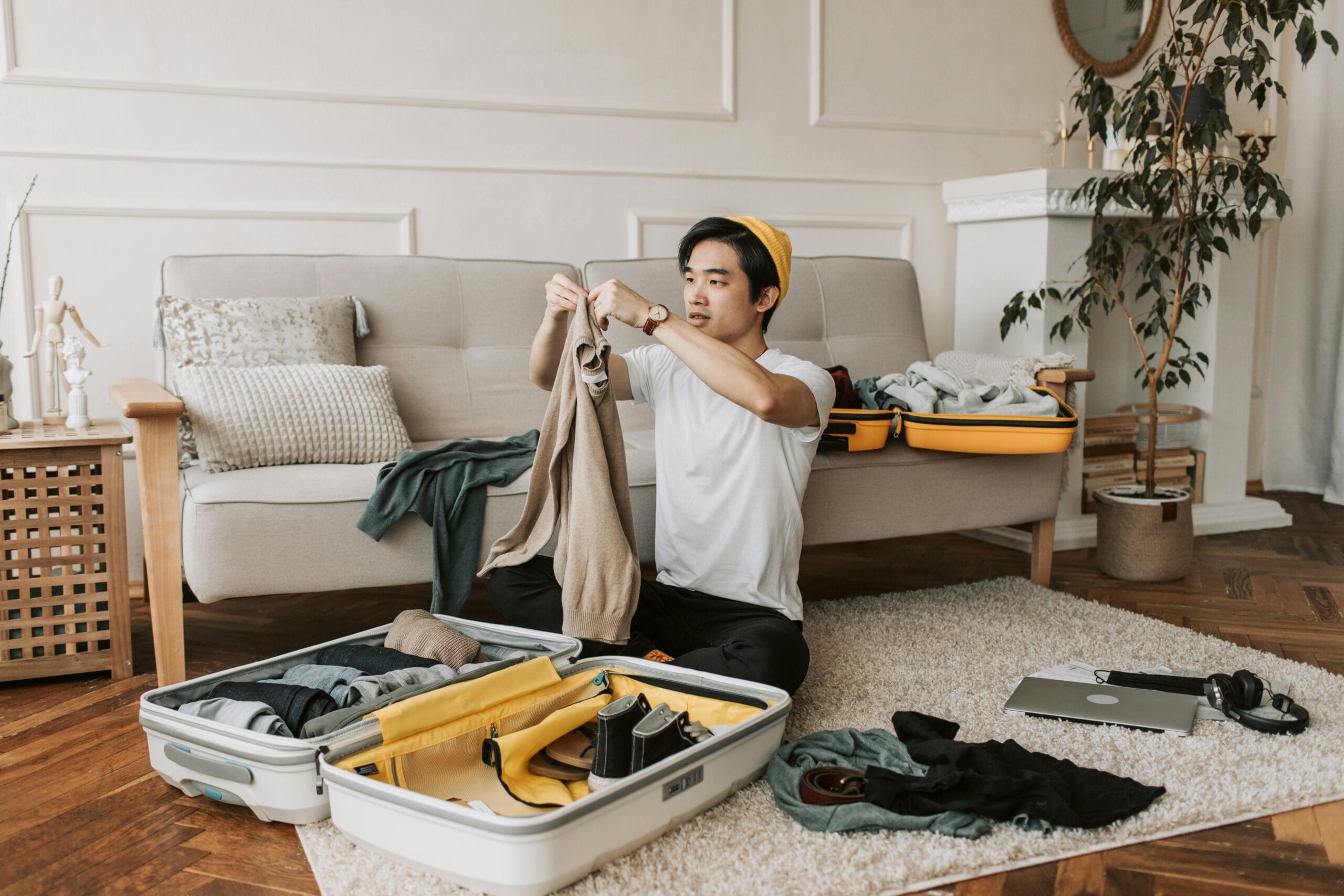 Customizable African Safari Packages: Tailor Your Perfect Adventure 1 A young man organizes clothes into a suitcase in a stylish living room, preparing for a trip.