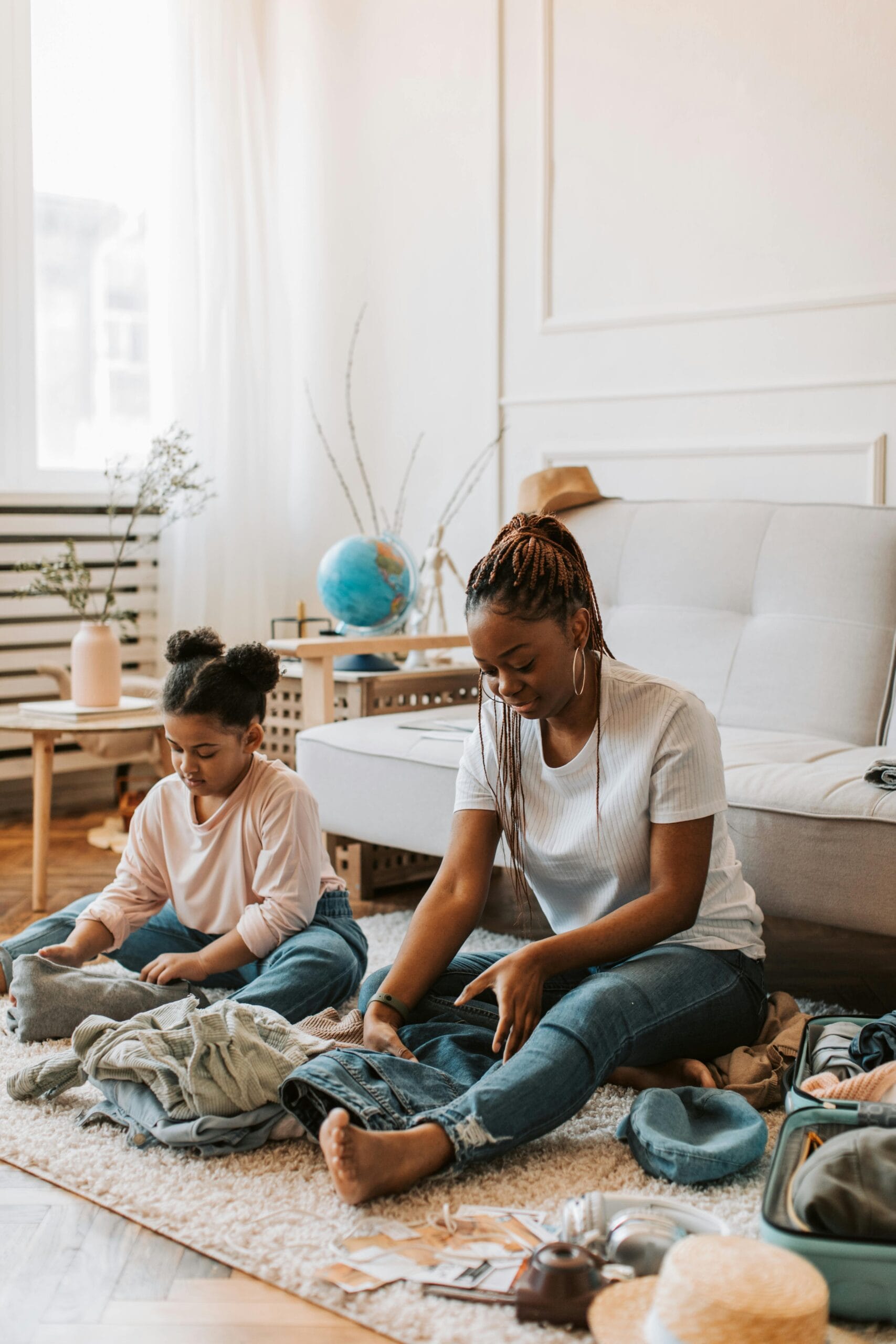 Packing tips for family safaris 1 A mother and daughter sit on the floor, packing clothes in a living room.