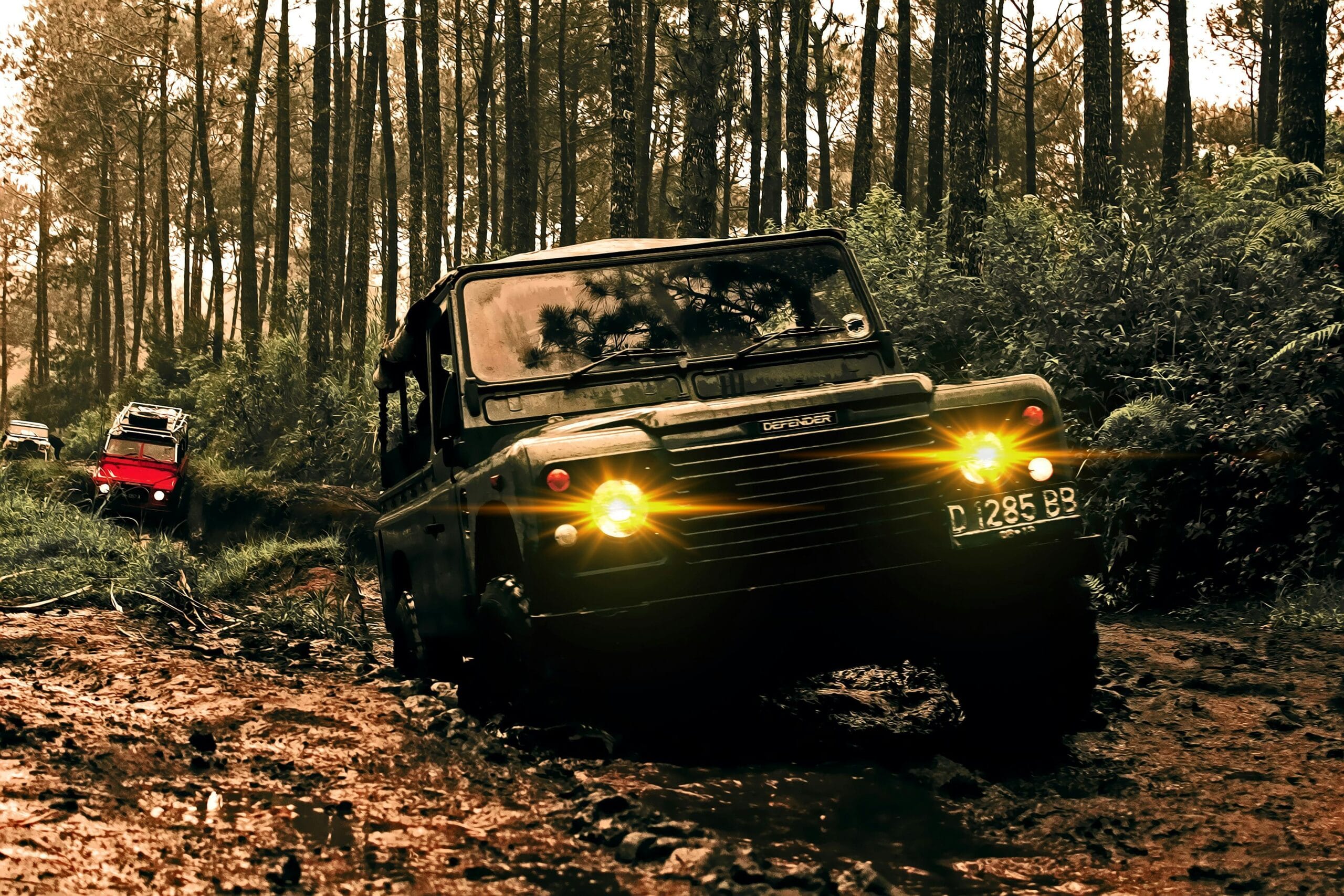 Rugged SUVs navigate muddy terrain in Parongpong, Indonesia forest.